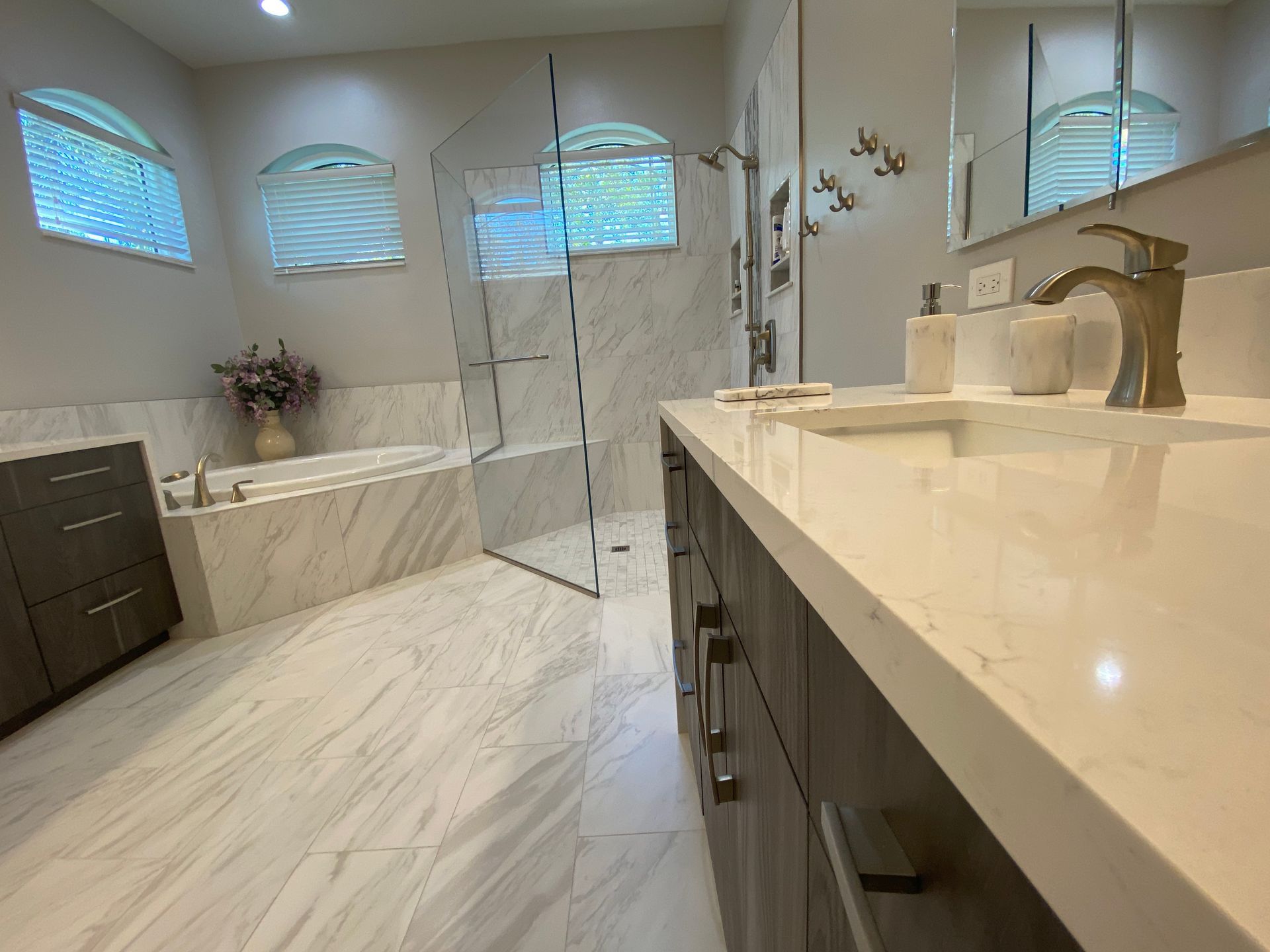 Luxurious bathroom with marble tile, glass shower, and vanity.