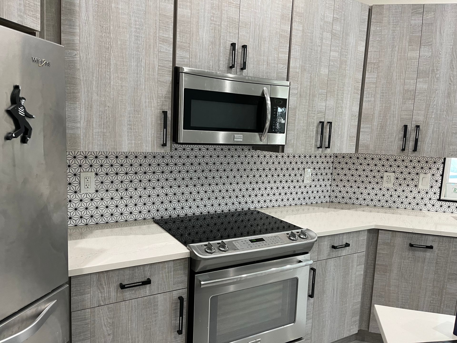 Kitchen with light gray cabinets, stainless steel appliances, and a mosaic backsplash.