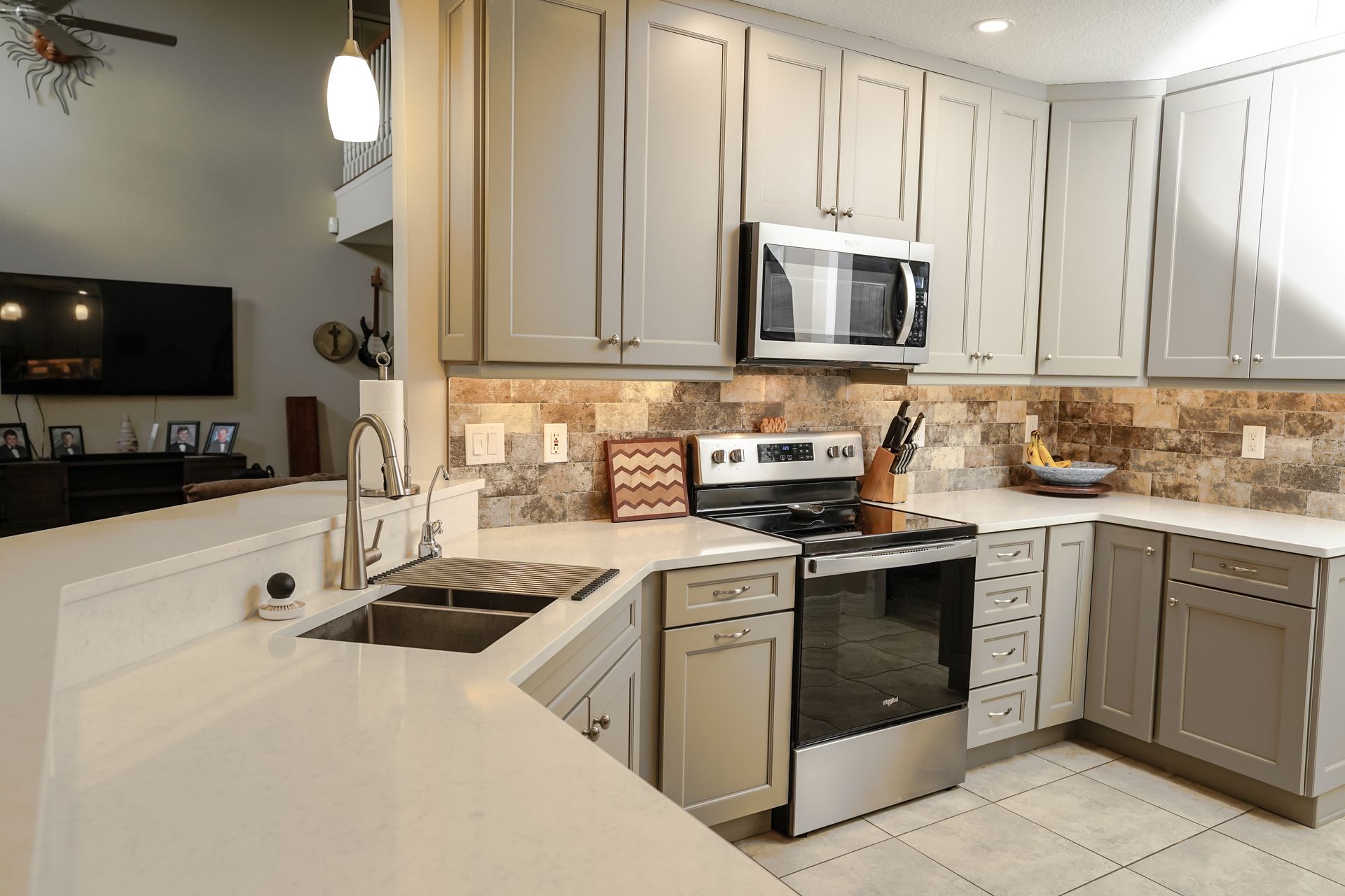 Modern kitchen with gray cabinets, stainless steel appliances, and white countertops.