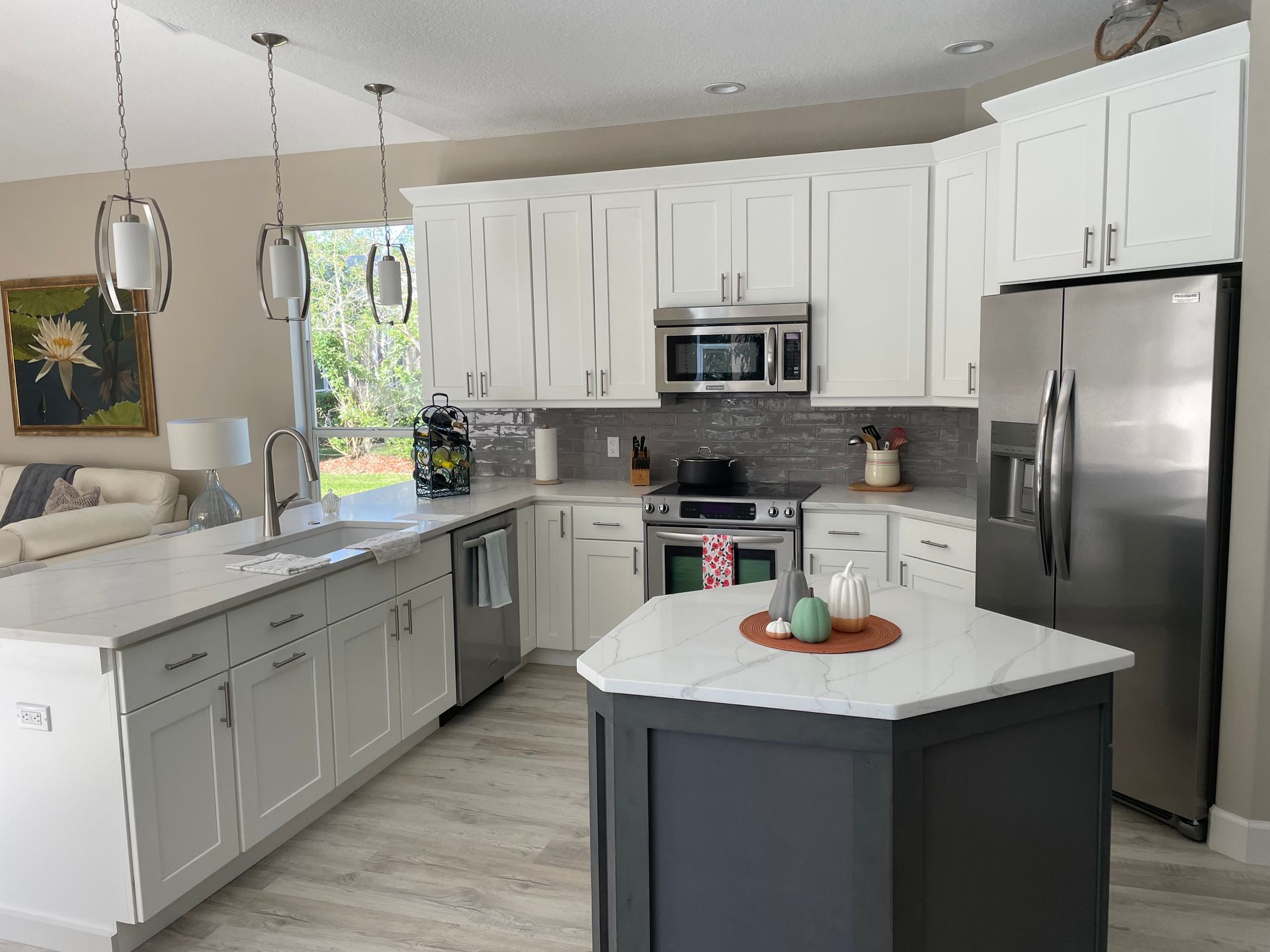 Modern kitchen with white cabinets, stainless steel appliances, and a gray island.
