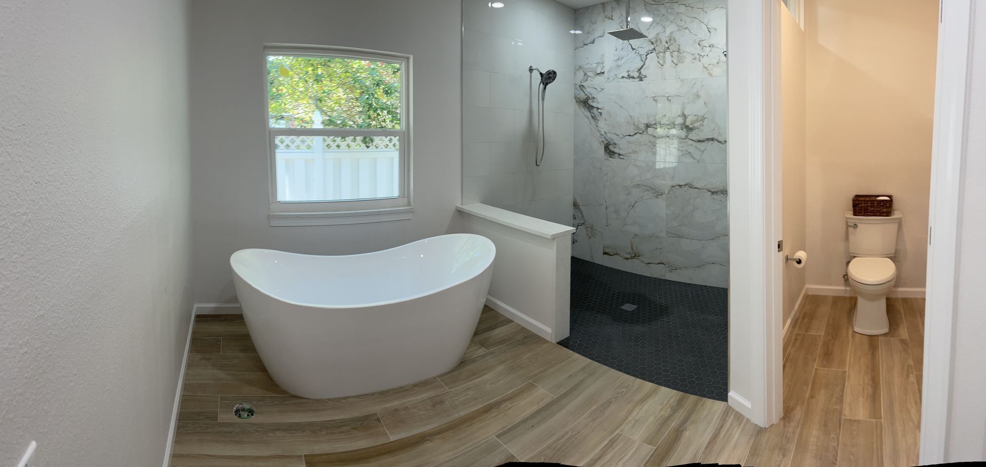 Modern bathroom with a freestanding tub, shower, and separate toilet room.