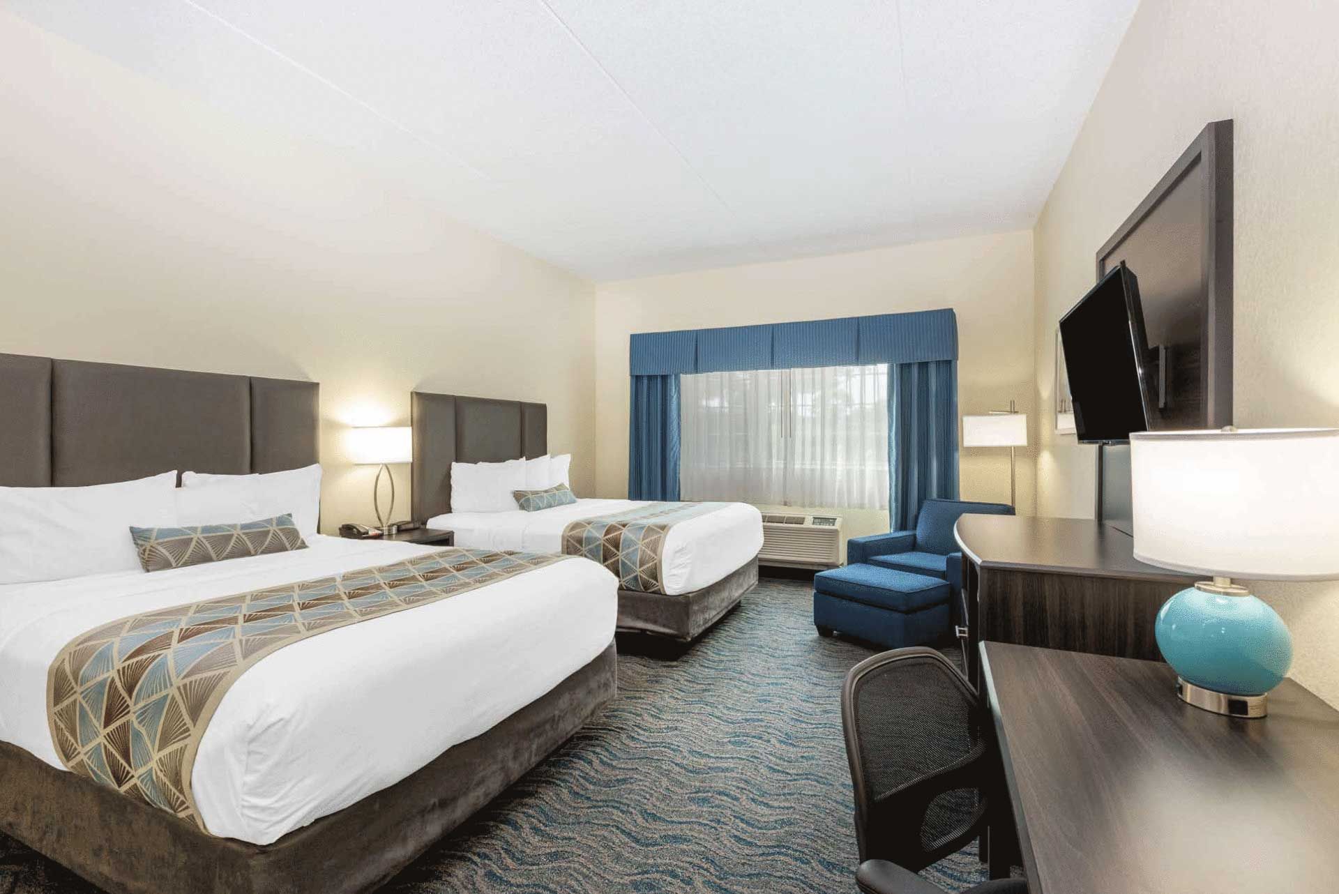 A hotel room with two beds , a desk and a television.