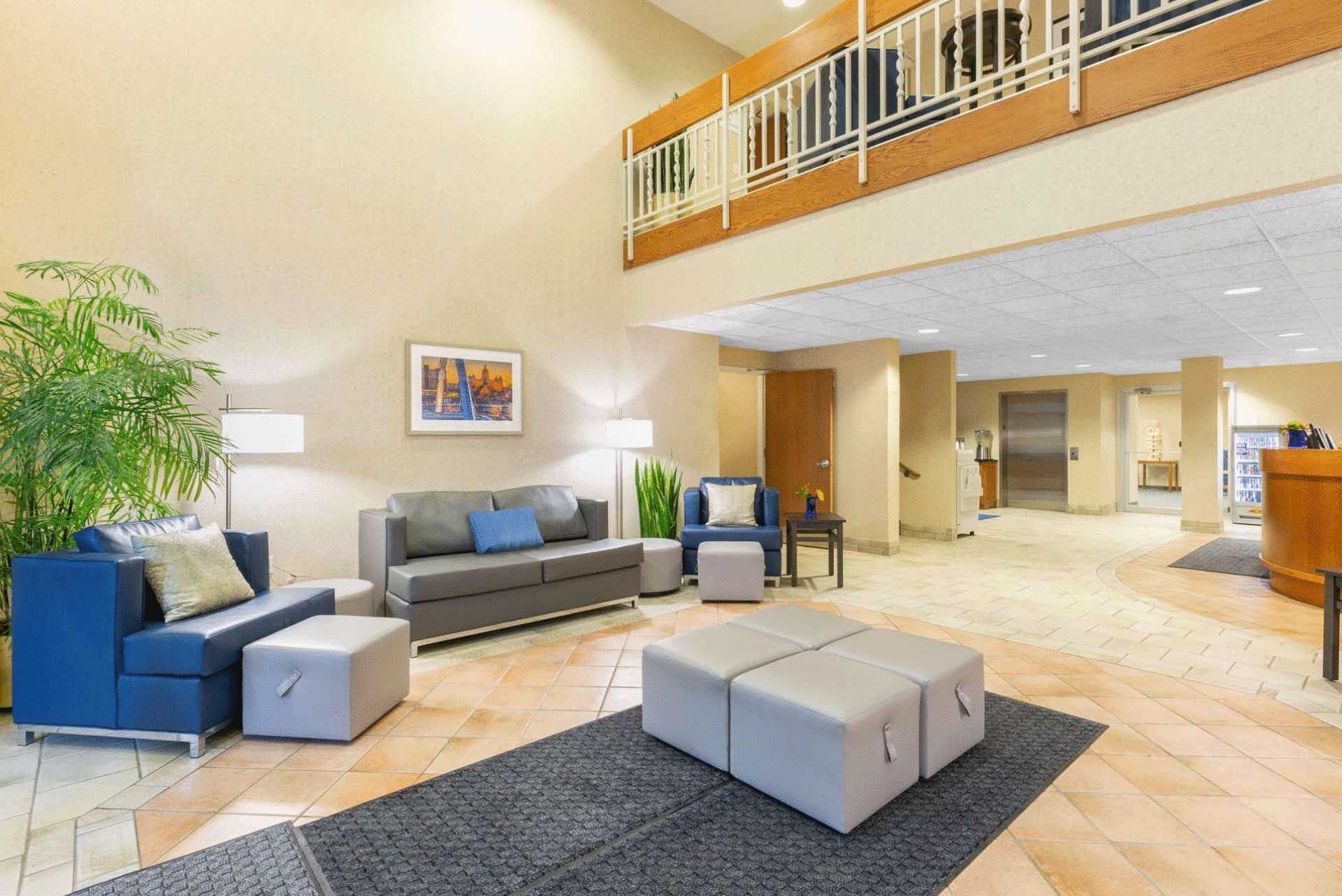A hotel lobby with a couch , chairs , and ottomans.