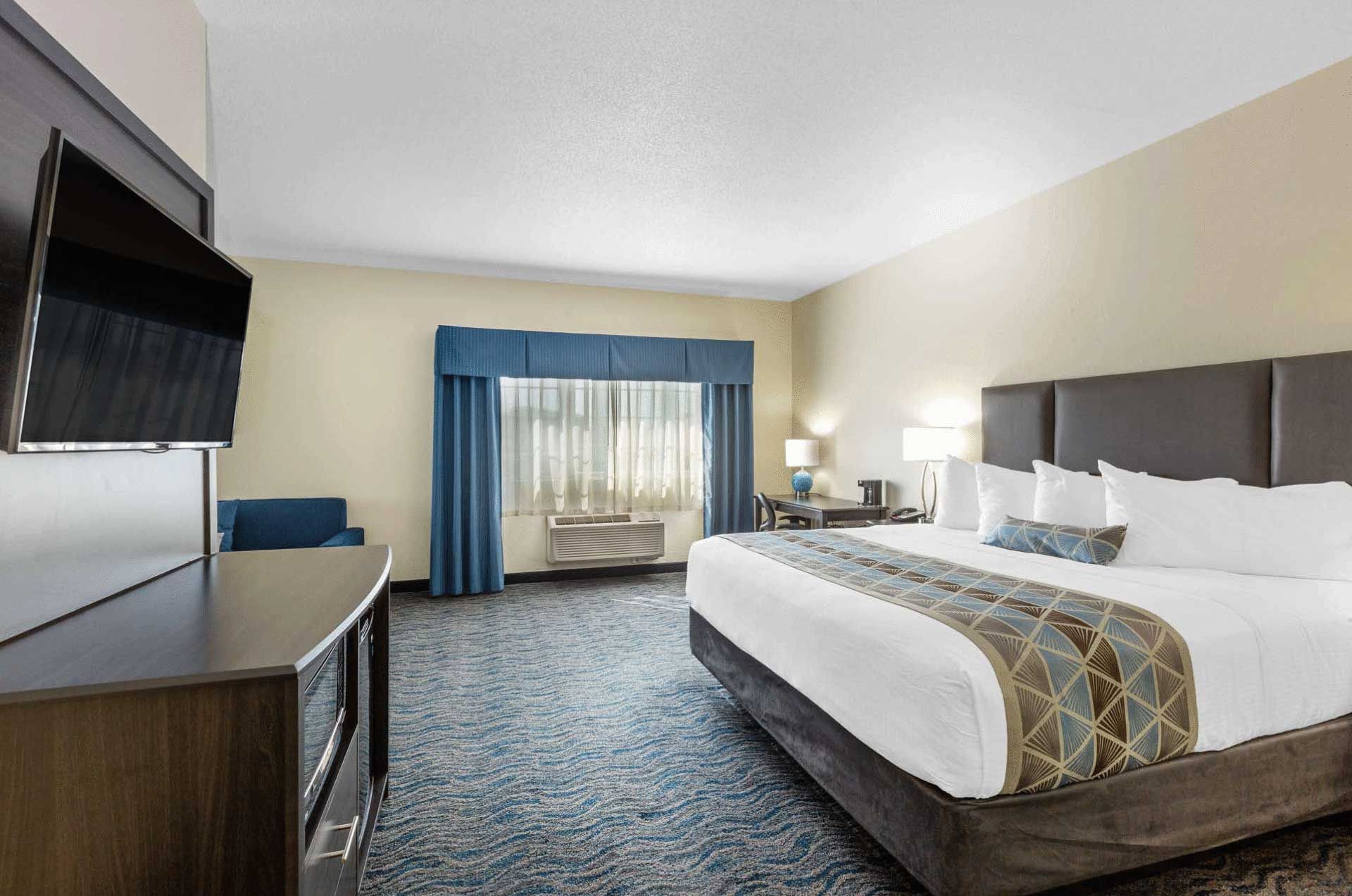 A hotel room with a king size bed and a flat screen tv.