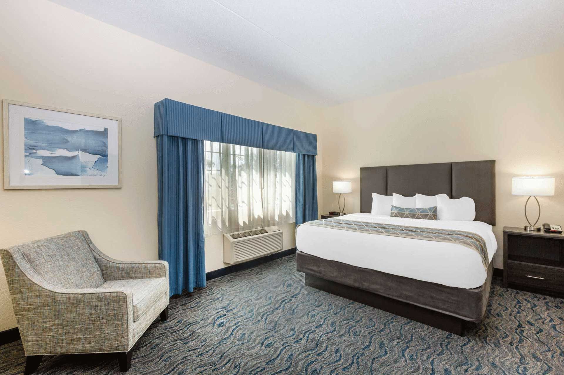 A hotel room with a king size bed and a chair.