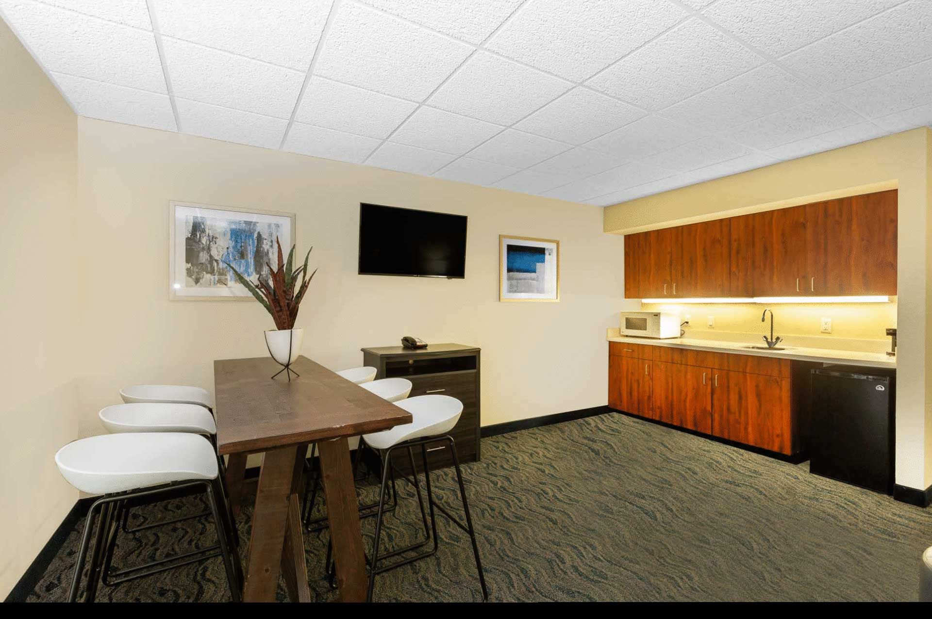 A kitchen with a table and chairs and a flat screen tv.