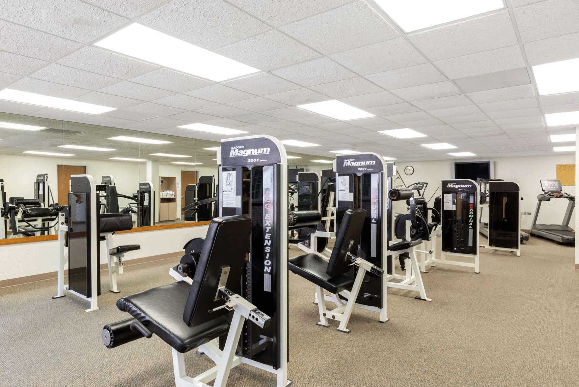 A gym with a lot of exercise equipment and a large mirror.