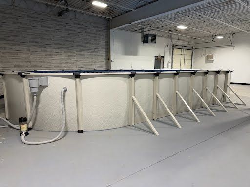 Large white cylindrical tank with metal frame and hoses in an industrial warehouse interior