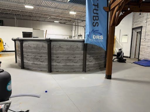 Indoor gym with a gray circular counter, blue banner, and a wood post on a polished concrete floor