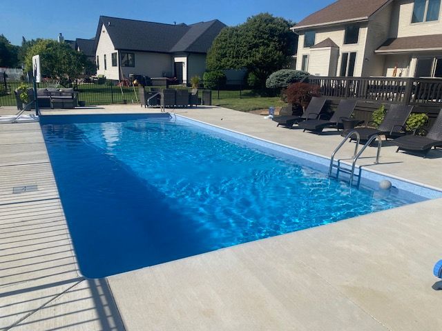 Outdoor residential swimming pool with blue water, lounge chairs, and houses in the background