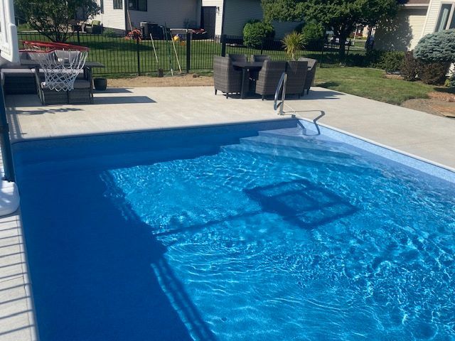 Backyard swimming pool with bright blue water and patio furniture nearby