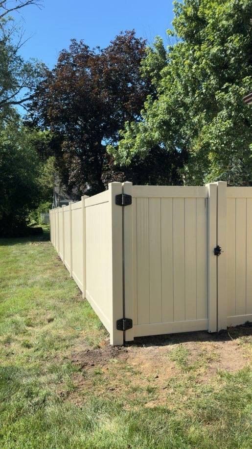 Cream-colored wooden fence panel in a grassy yard with trees in the background