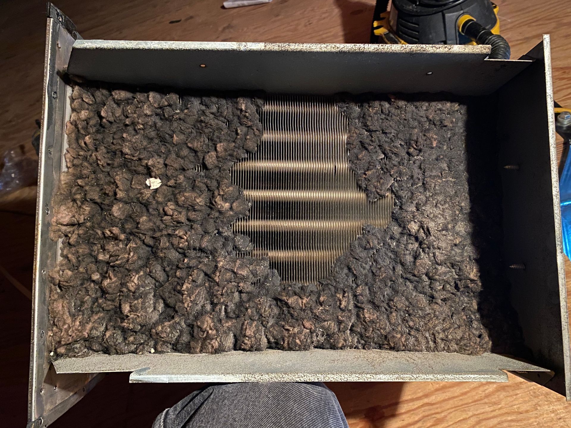 a dirty air vent is sitting on a wooden table next to a vacuum cleaner