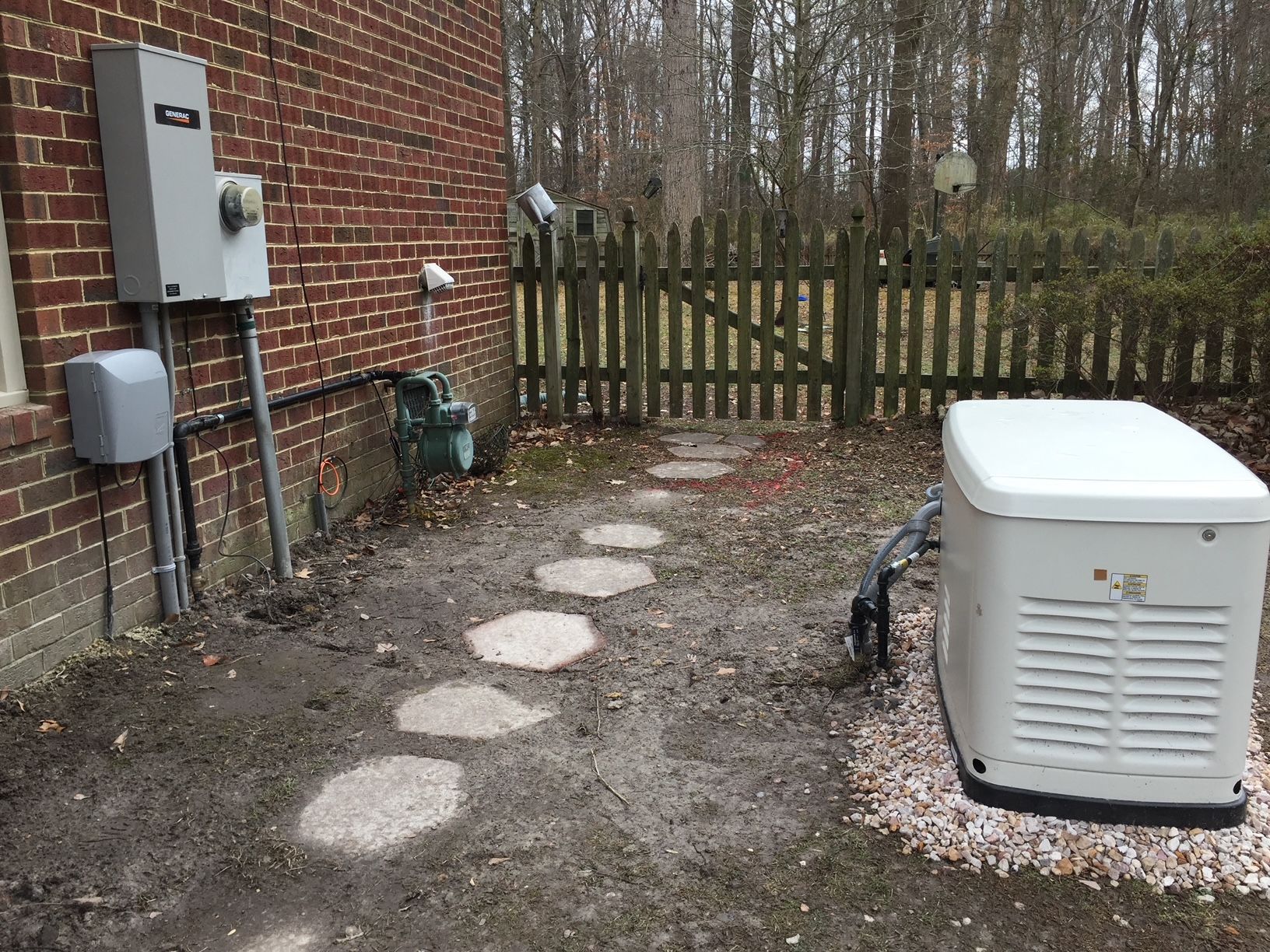 a white generator is sitting in the dirt in front of a brick building 