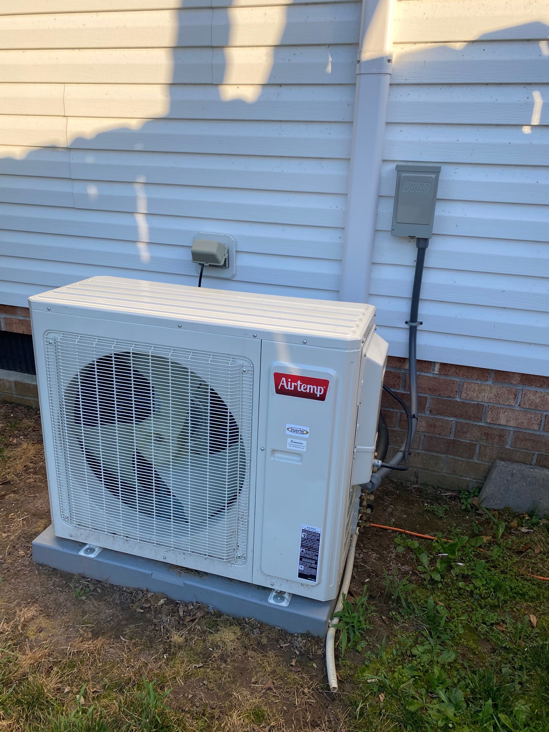 a white air conditioner is sitting on the side of a house