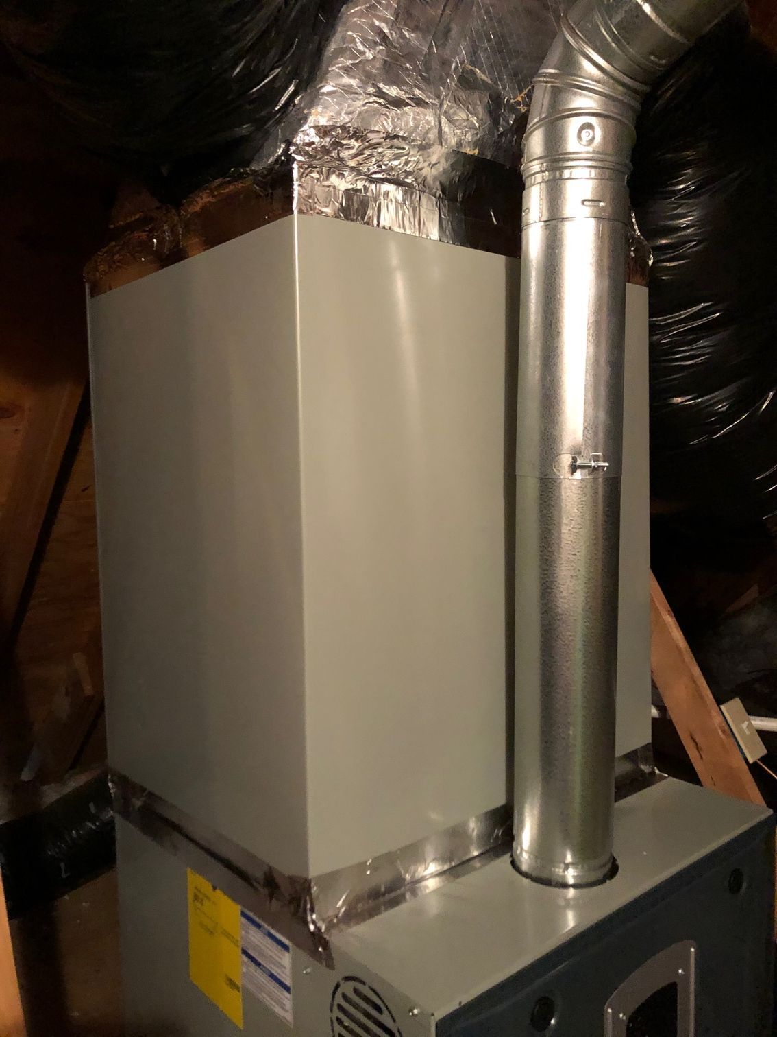 a furnace is sitting in the attic with a metal pipe coming out of it