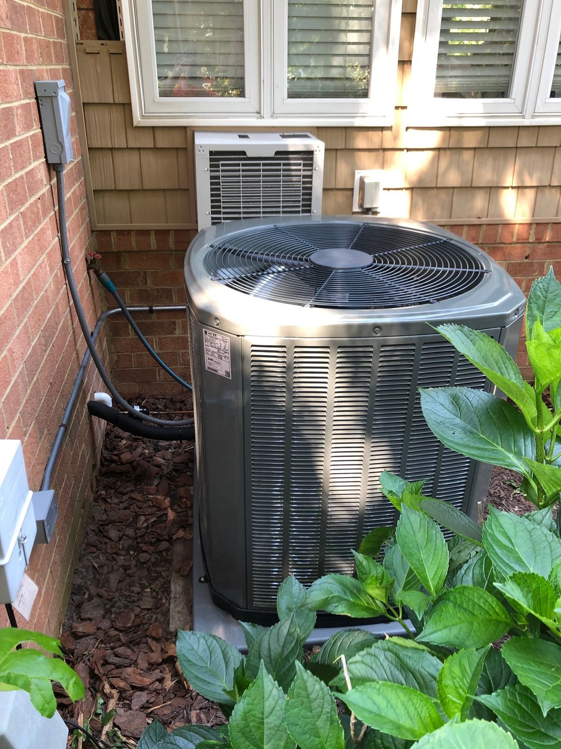 a large air conditioner is sitting on the side of a house next to a window