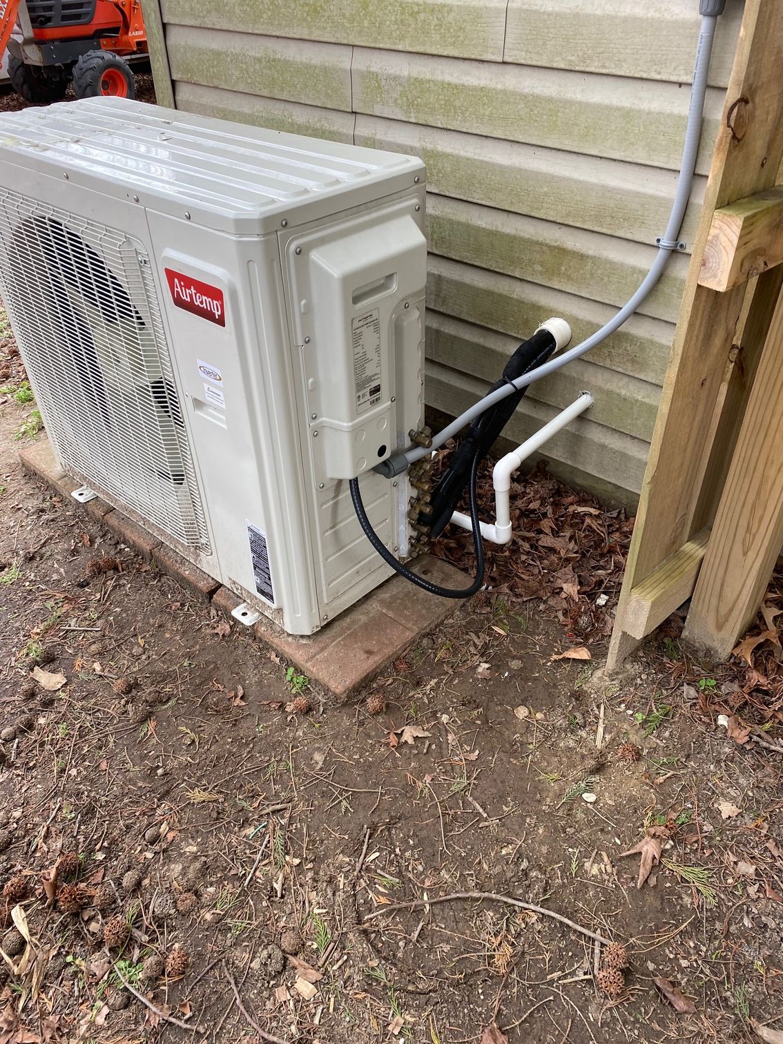 a white air conditioner is sitting on the ground next to a house