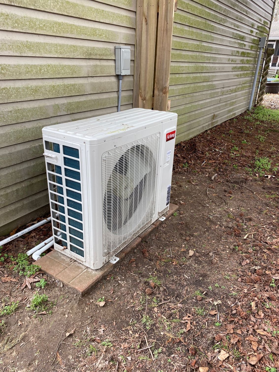 a white air conditioner is sitting on the side of a house