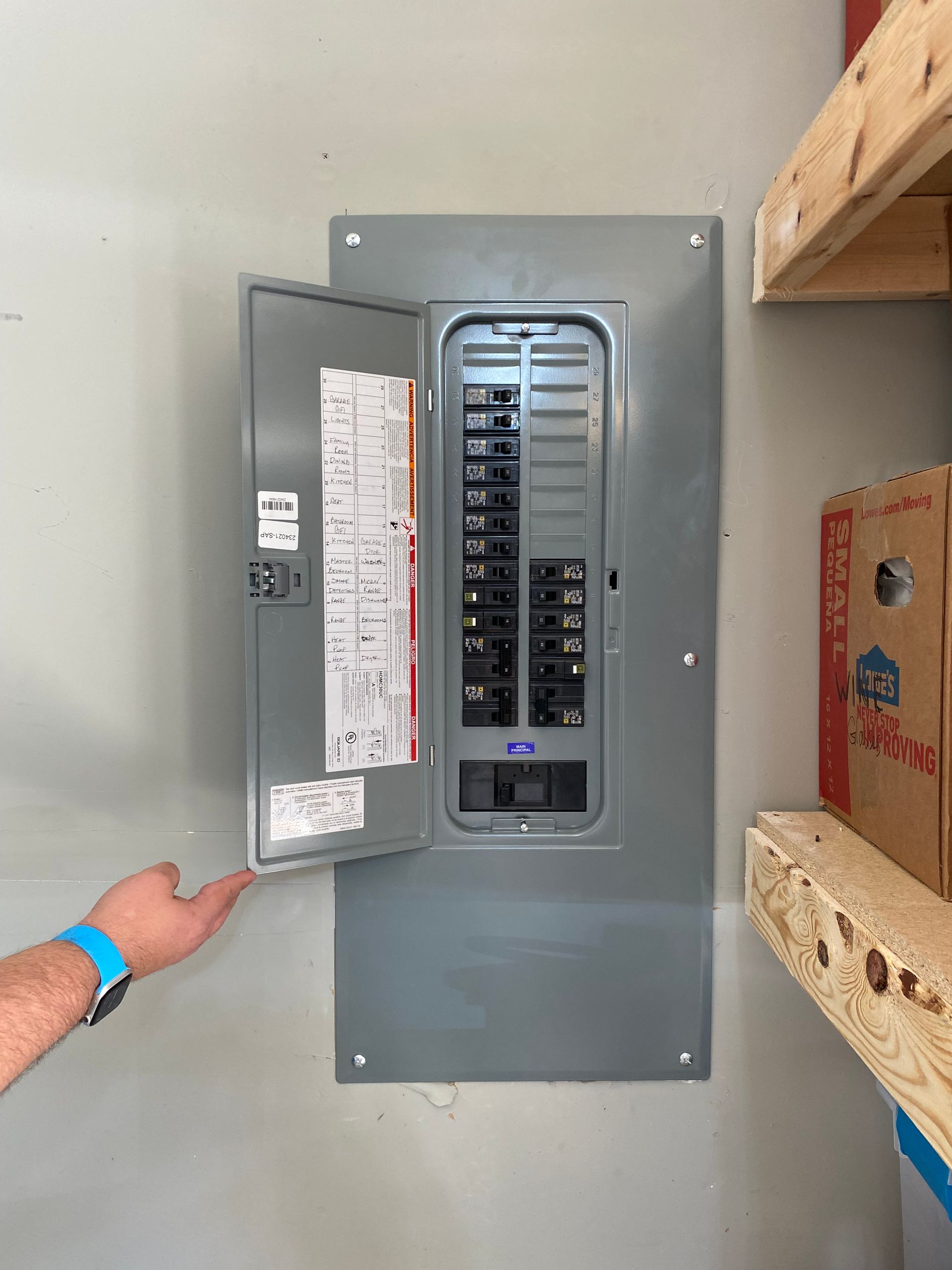 a person is pointing at an electrical box on a wall