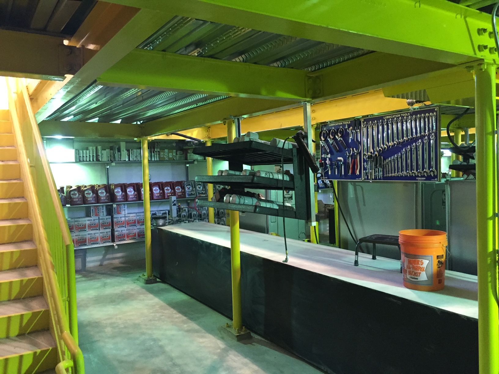 a warehouse with a yellow staircase and a bucket of oil