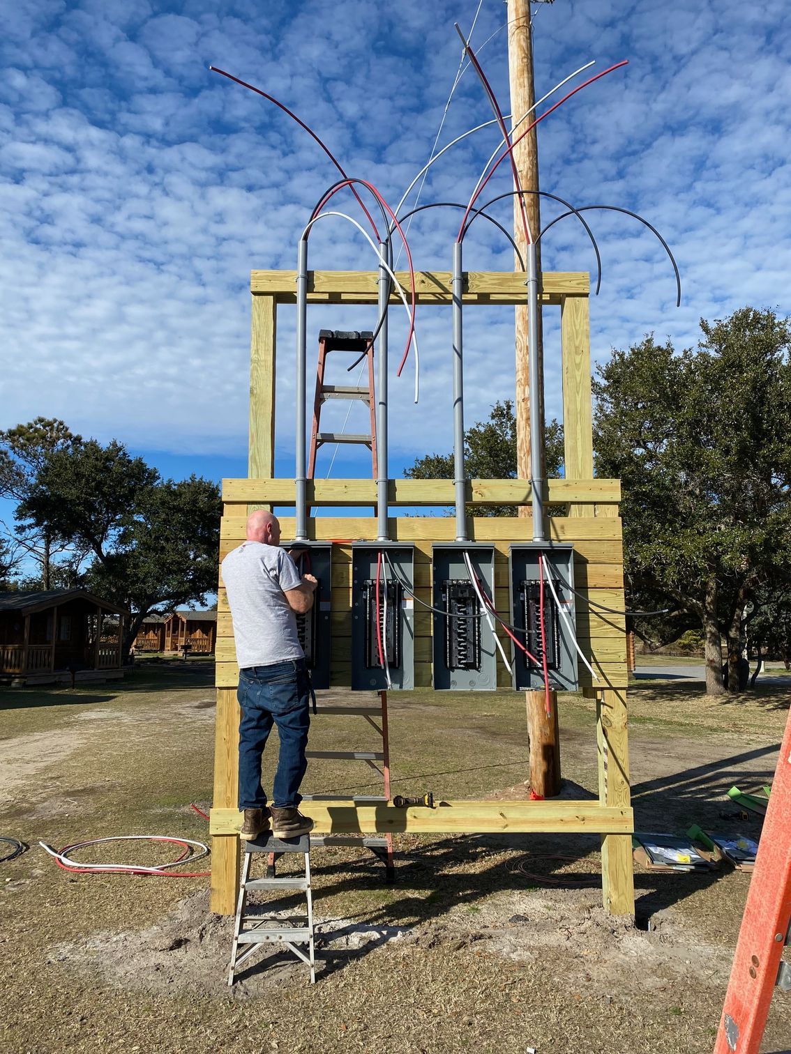 a man is standing on a ladder in front of a wooden structure