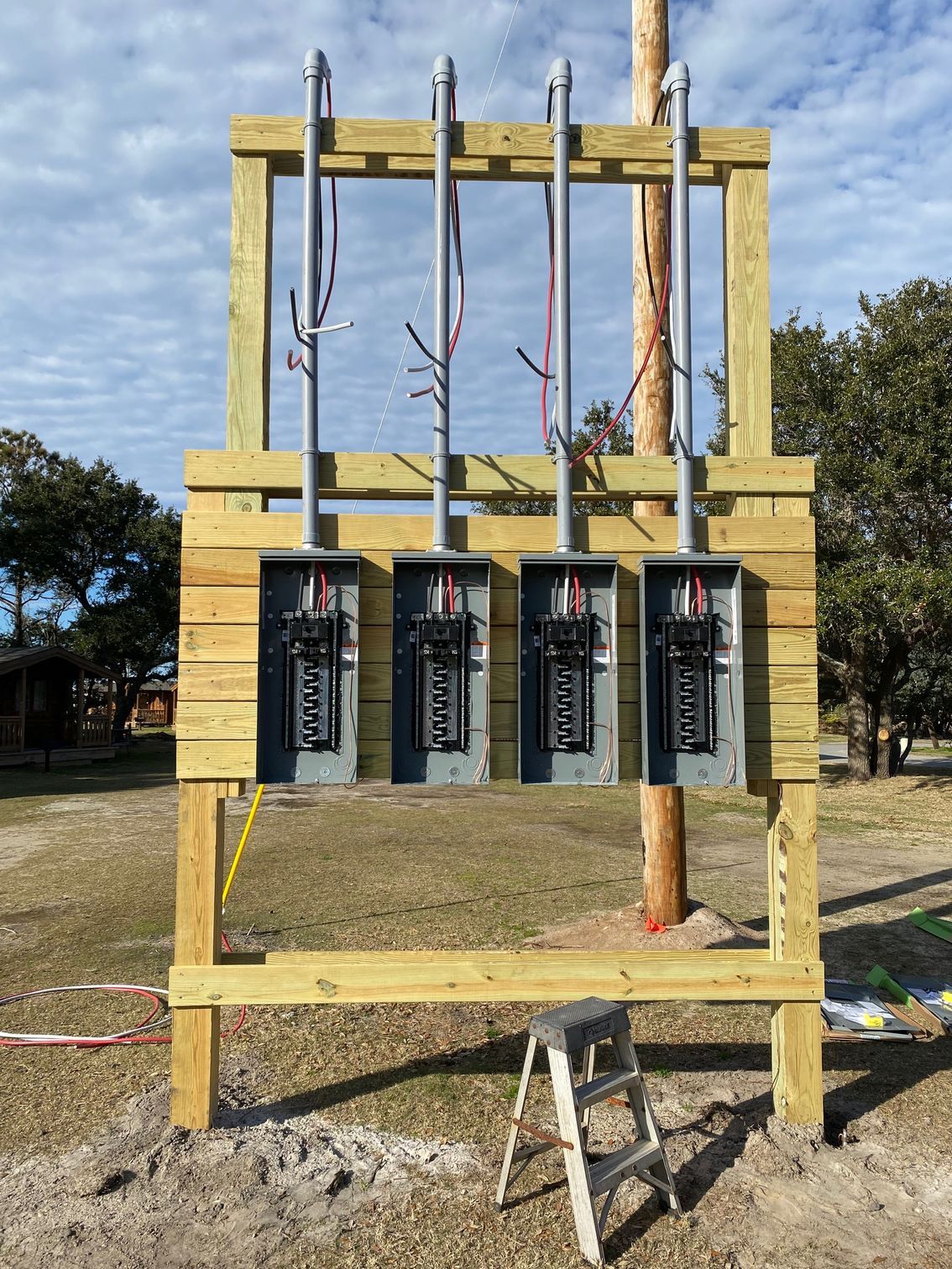 a ladder is sitting next to a wooden structure with three electrical panels on it