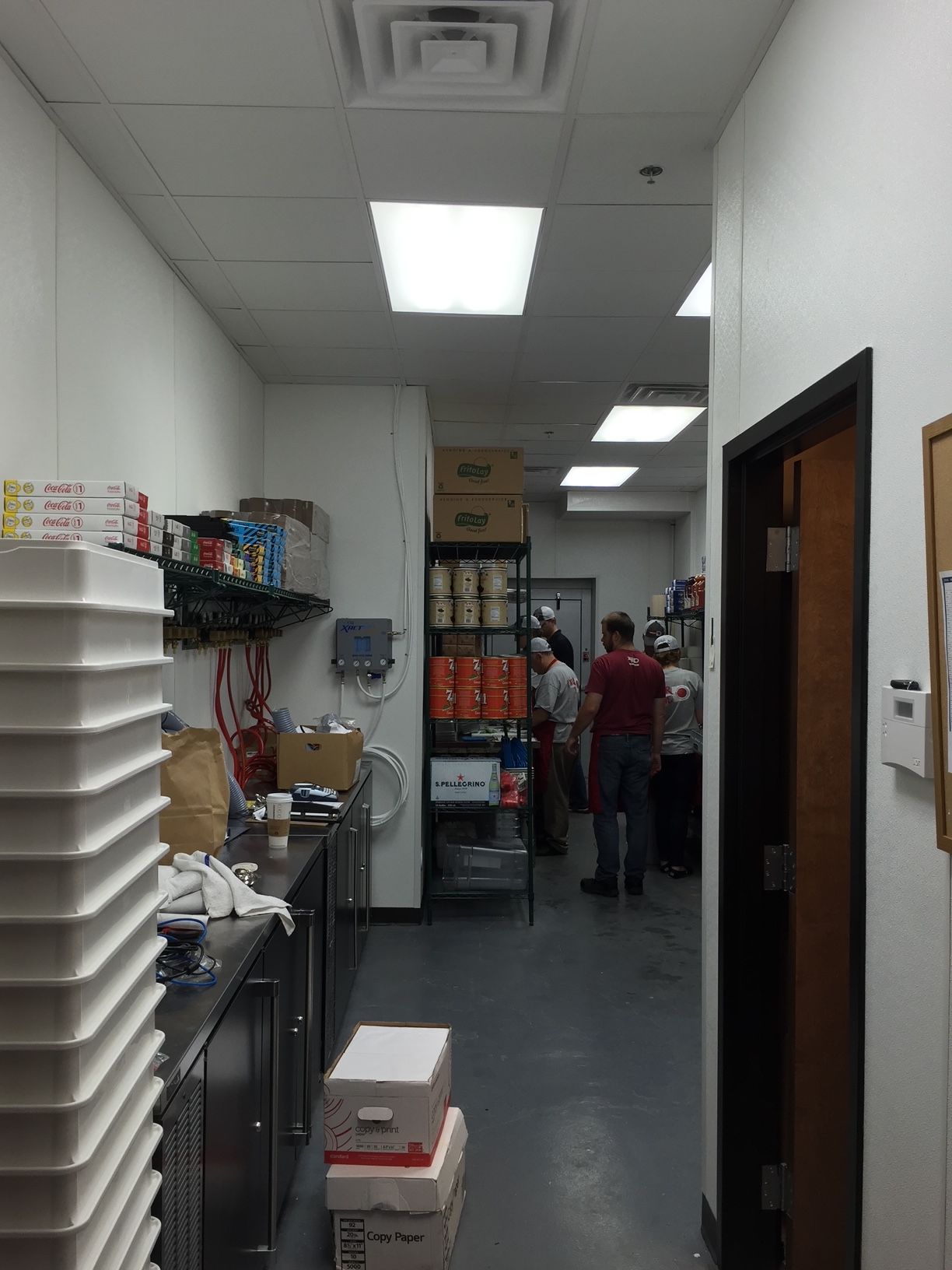 a group of people are standing in a hallway in a kitchen 