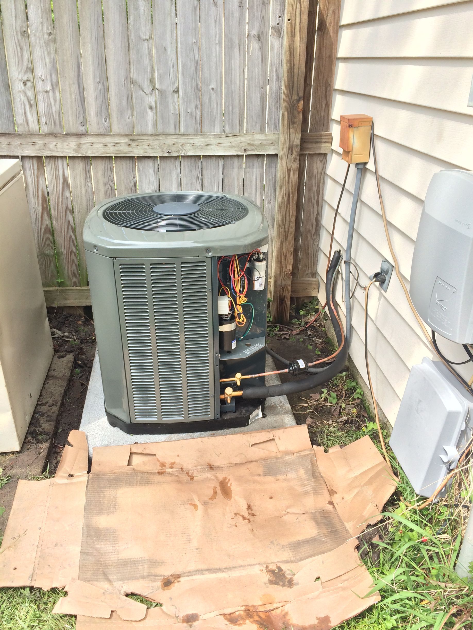 an air conditioner is sitting on the side of a house next to a fence 