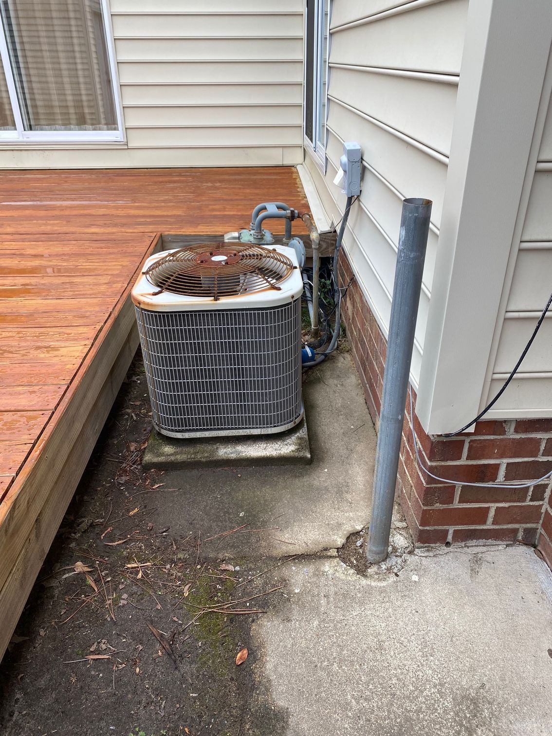 an air conditioner is sitting on the side of a house next to a wooden deck