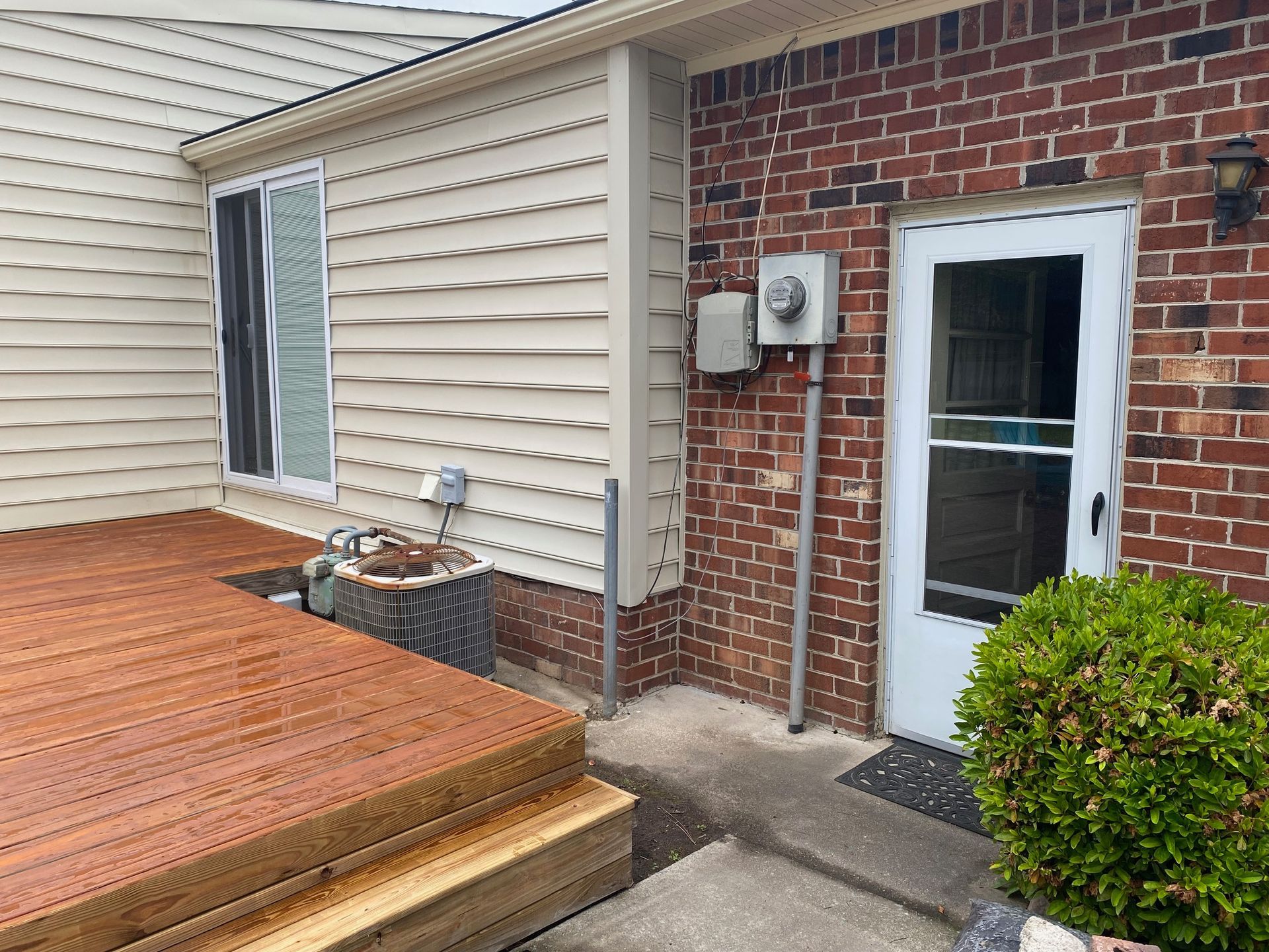 a brick house with a wooden deck and a white door
