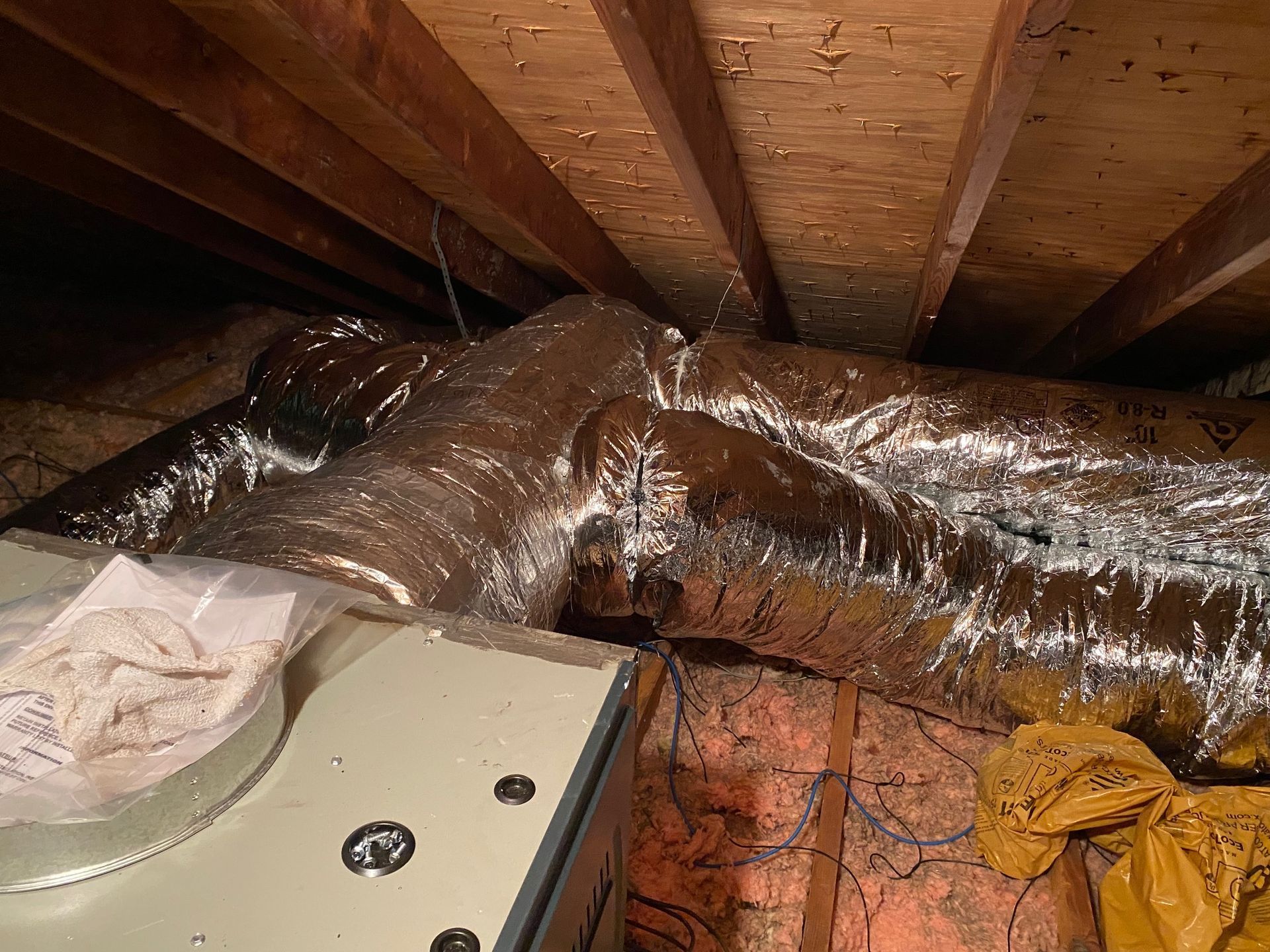a bunch of ducts are hanging from the ceiling of an attic