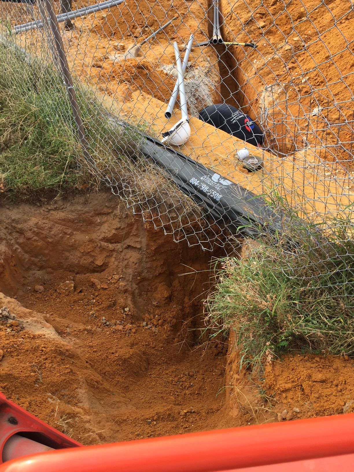 a hole in the ground with a fence in the background 