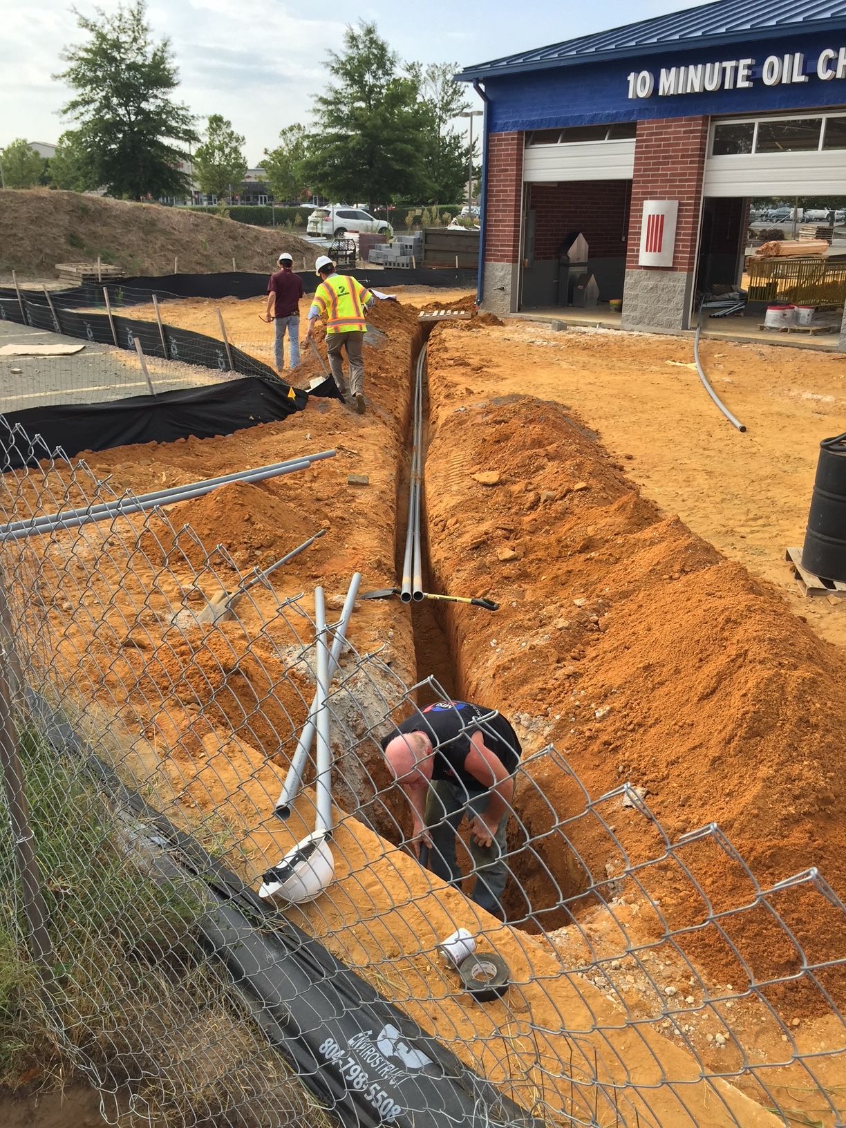 a man is digging a hole in the ground in front of a gas station 
