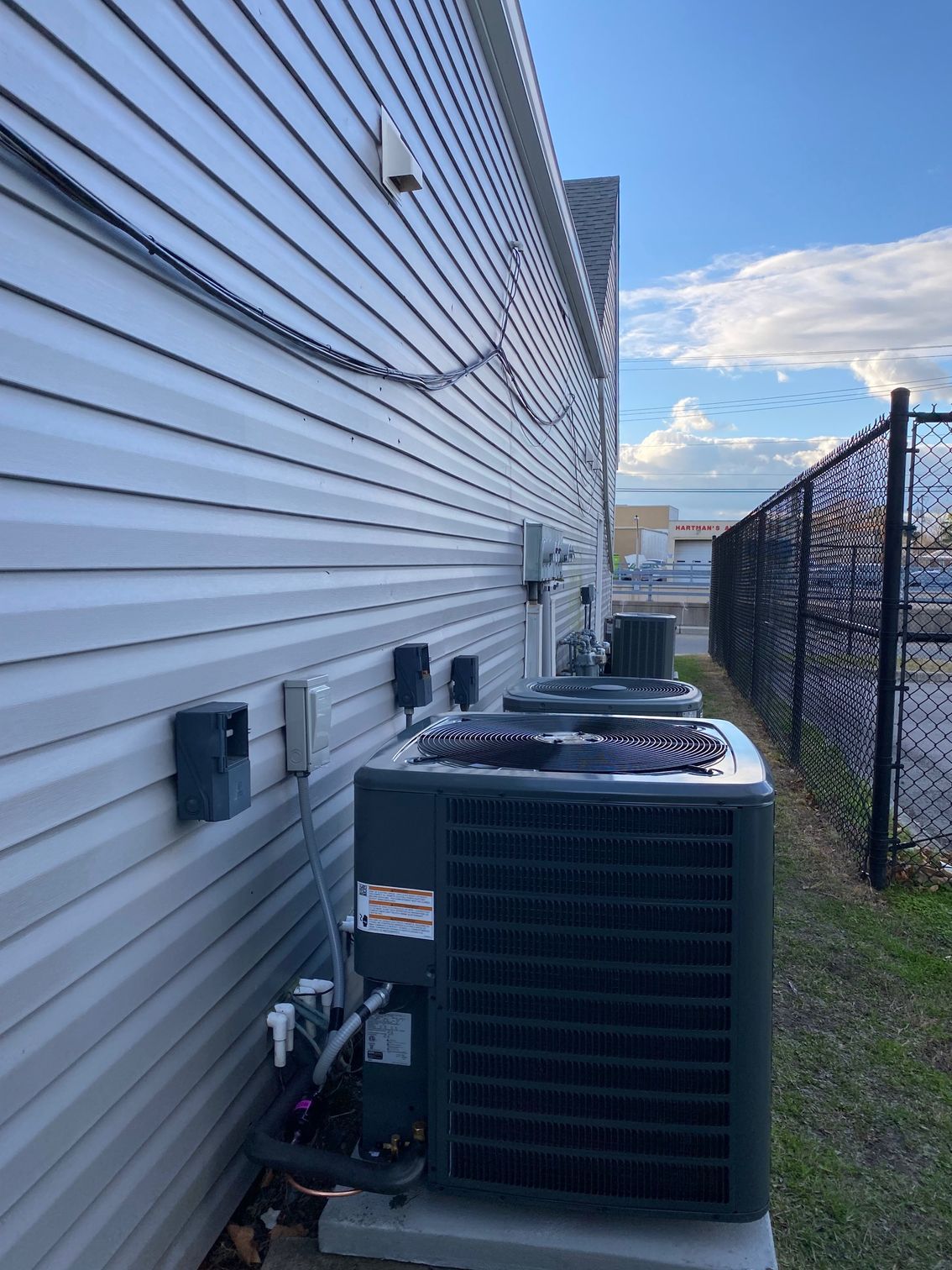 a row of air conditioners are sitting on the side of a building next to a chain link fence