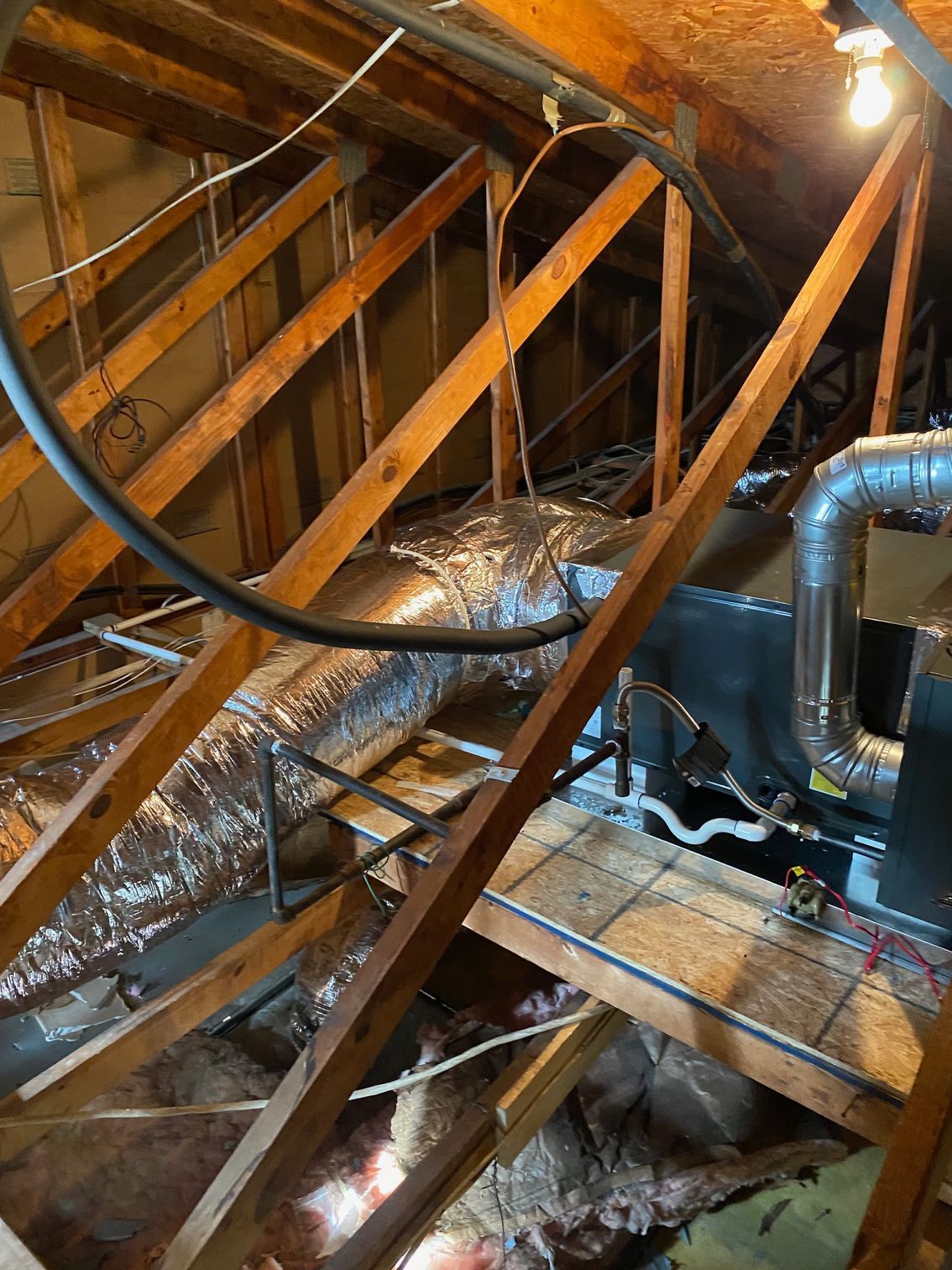 an attic with a lot of pipes and wires hanging from the ceiling