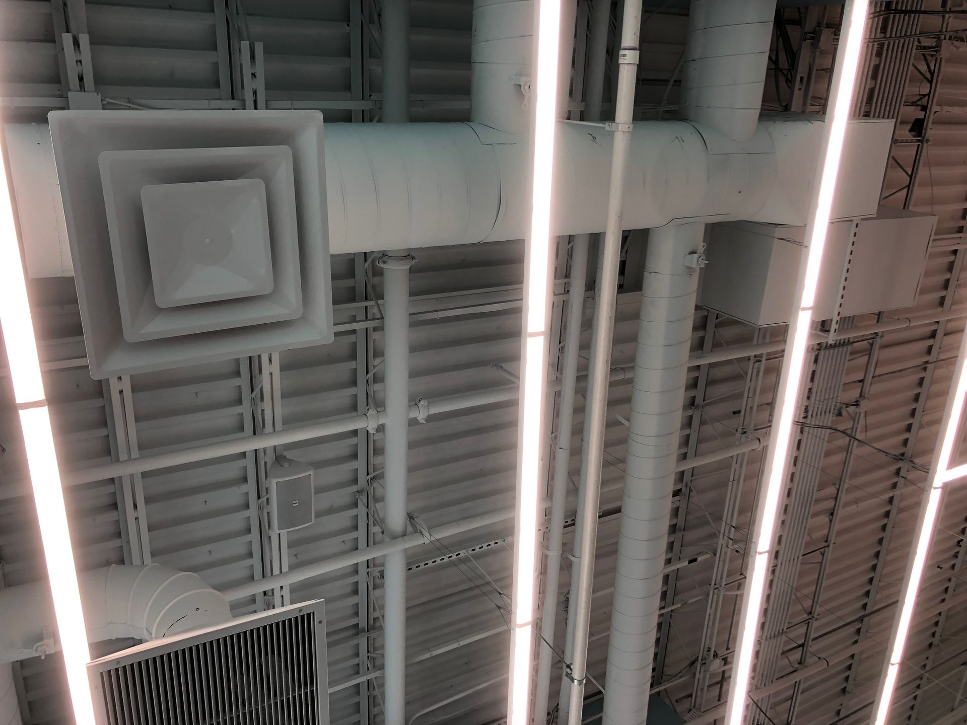 a ceiling with a lot of pipes and lights hanging from it