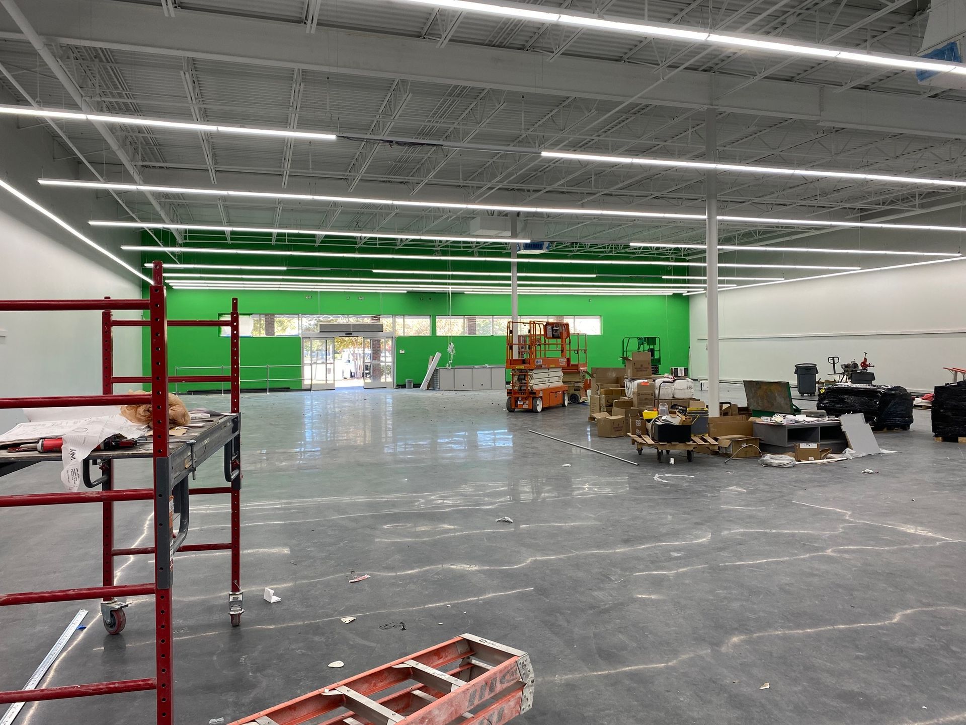 a large empty room with a green wall and a red ladder