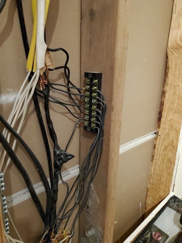 a bunch of wires are hanging from a wooden wall 