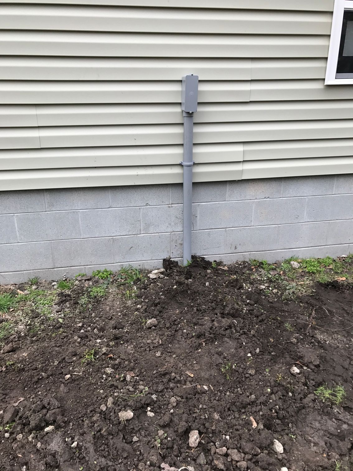 a pipe is sitting in the dirt in front of a house 