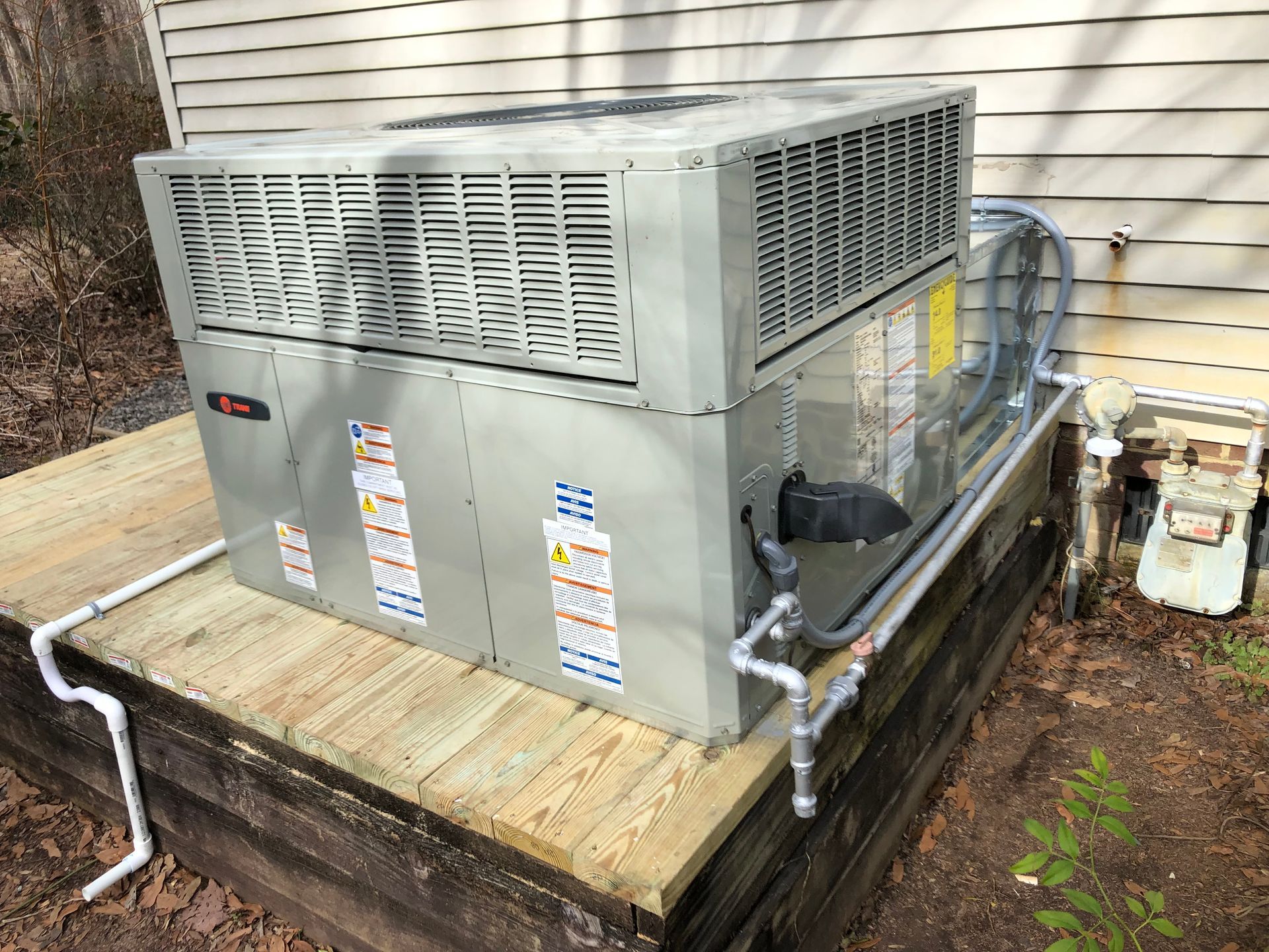 a large air conditioner is sitting on top of a wooden platform next to a house