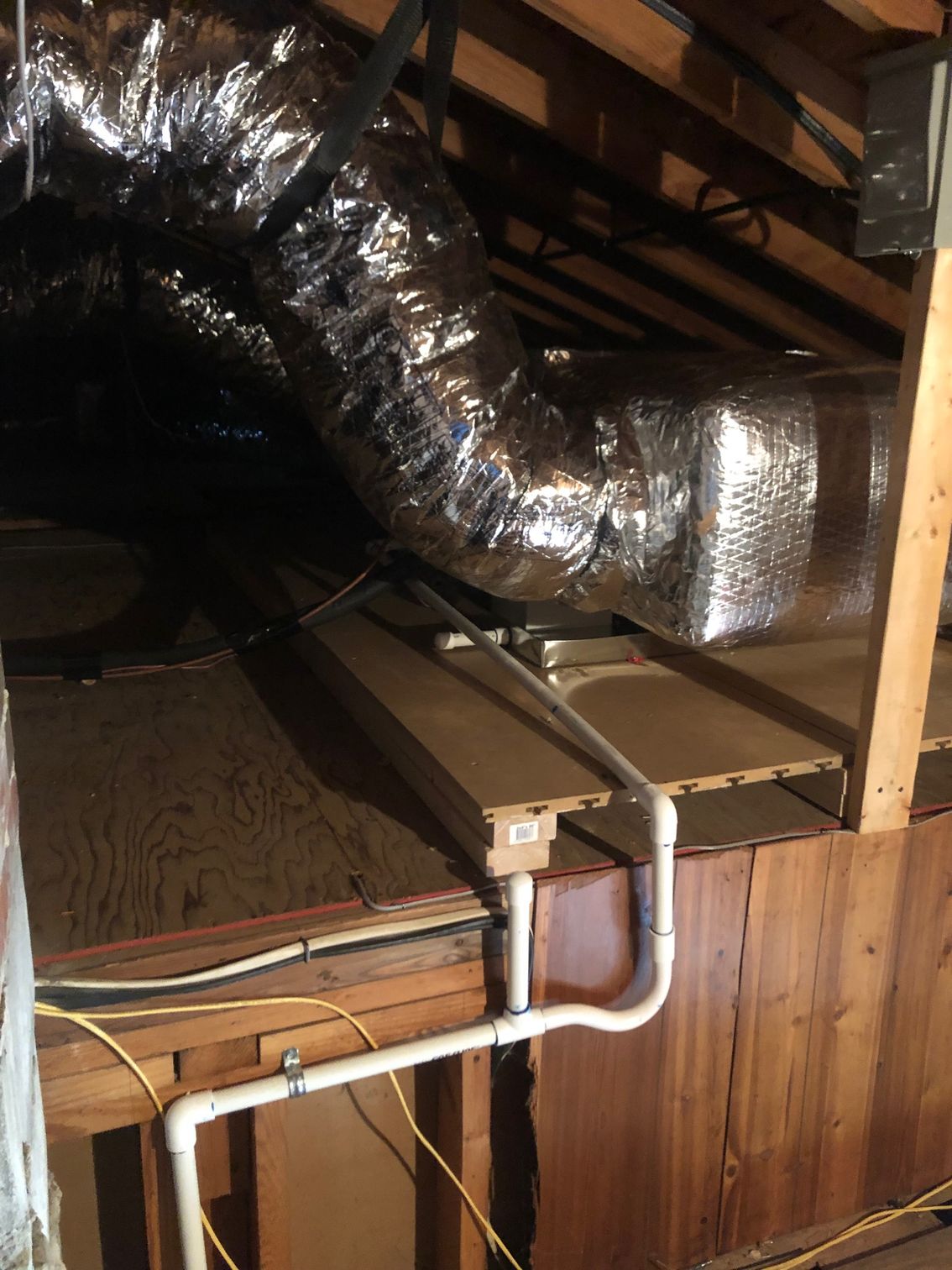 an attic with a duct and pipes in it