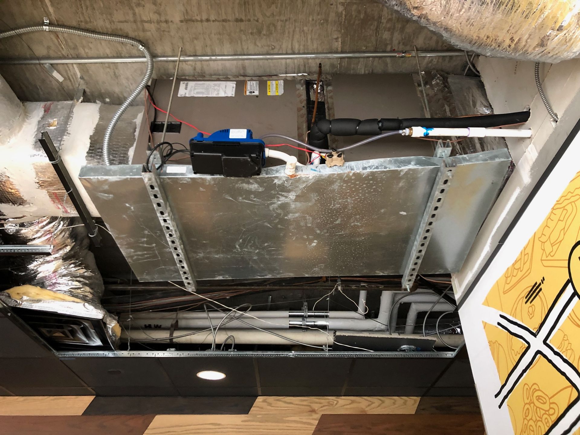 a ceiling with a lot of pipes and wires hanging from it