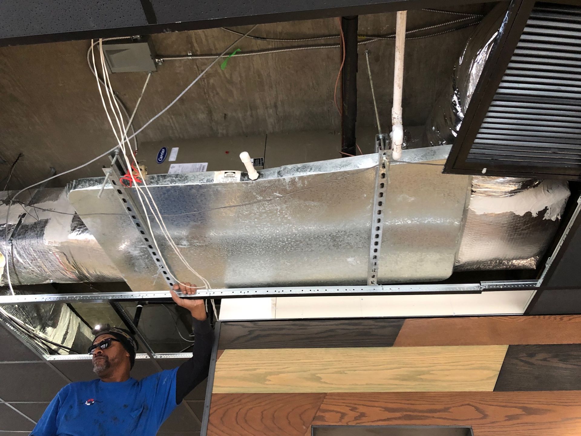a man in a blue shirt is working on the ceiling of a building