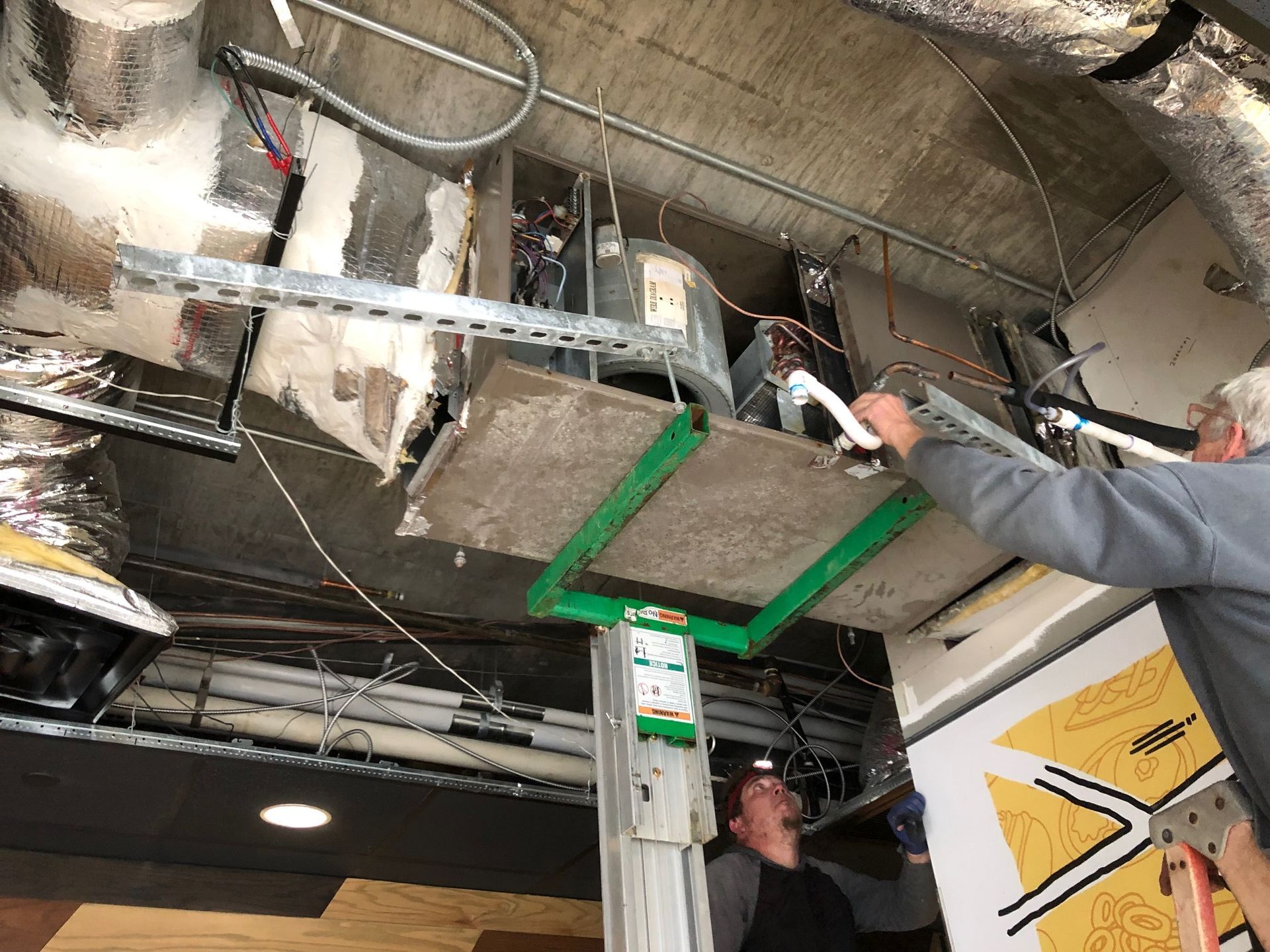 a man is working on a ceiling vent in a building