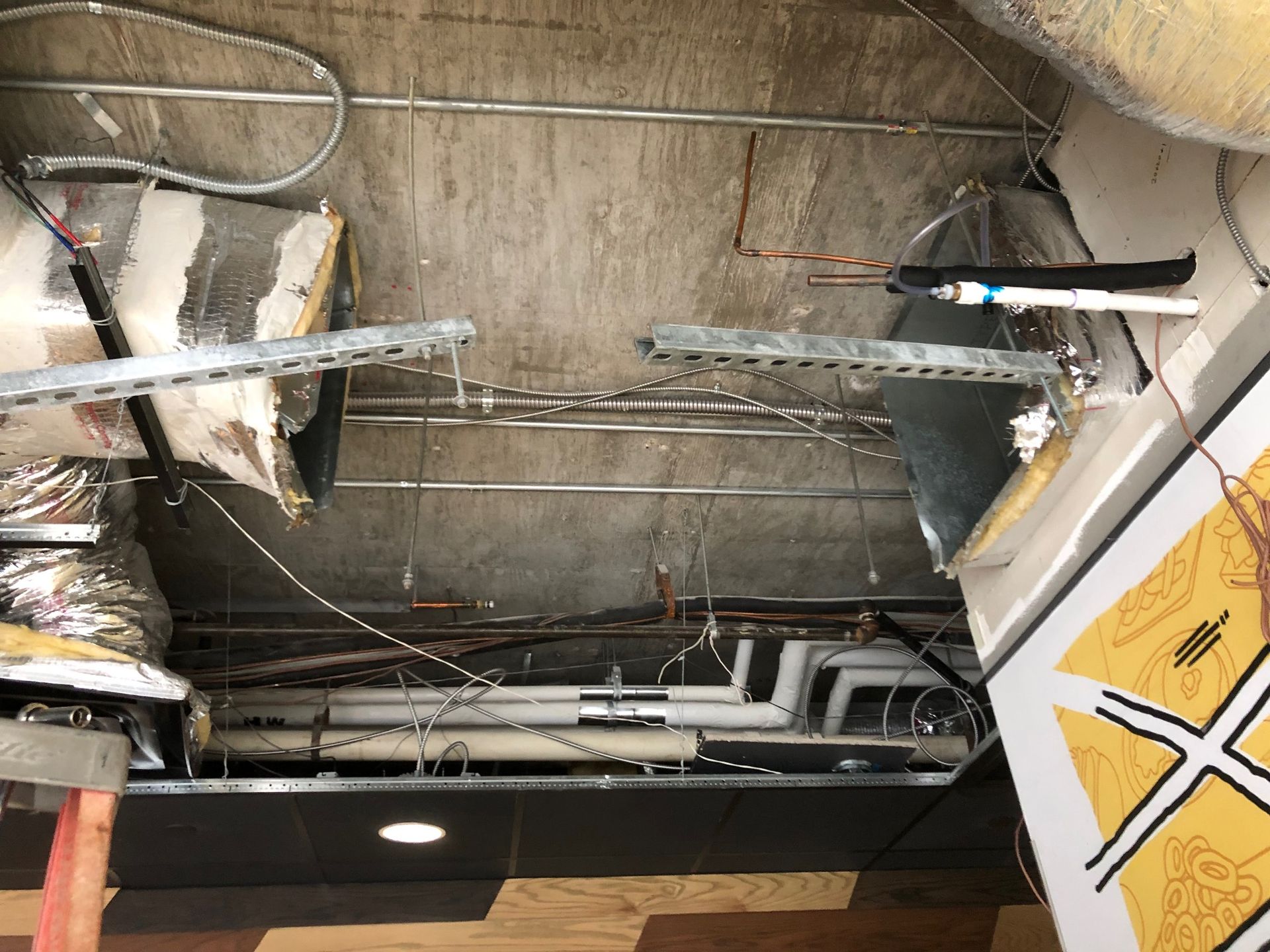 a ceiling with a lot of pipes and wires hanging from it