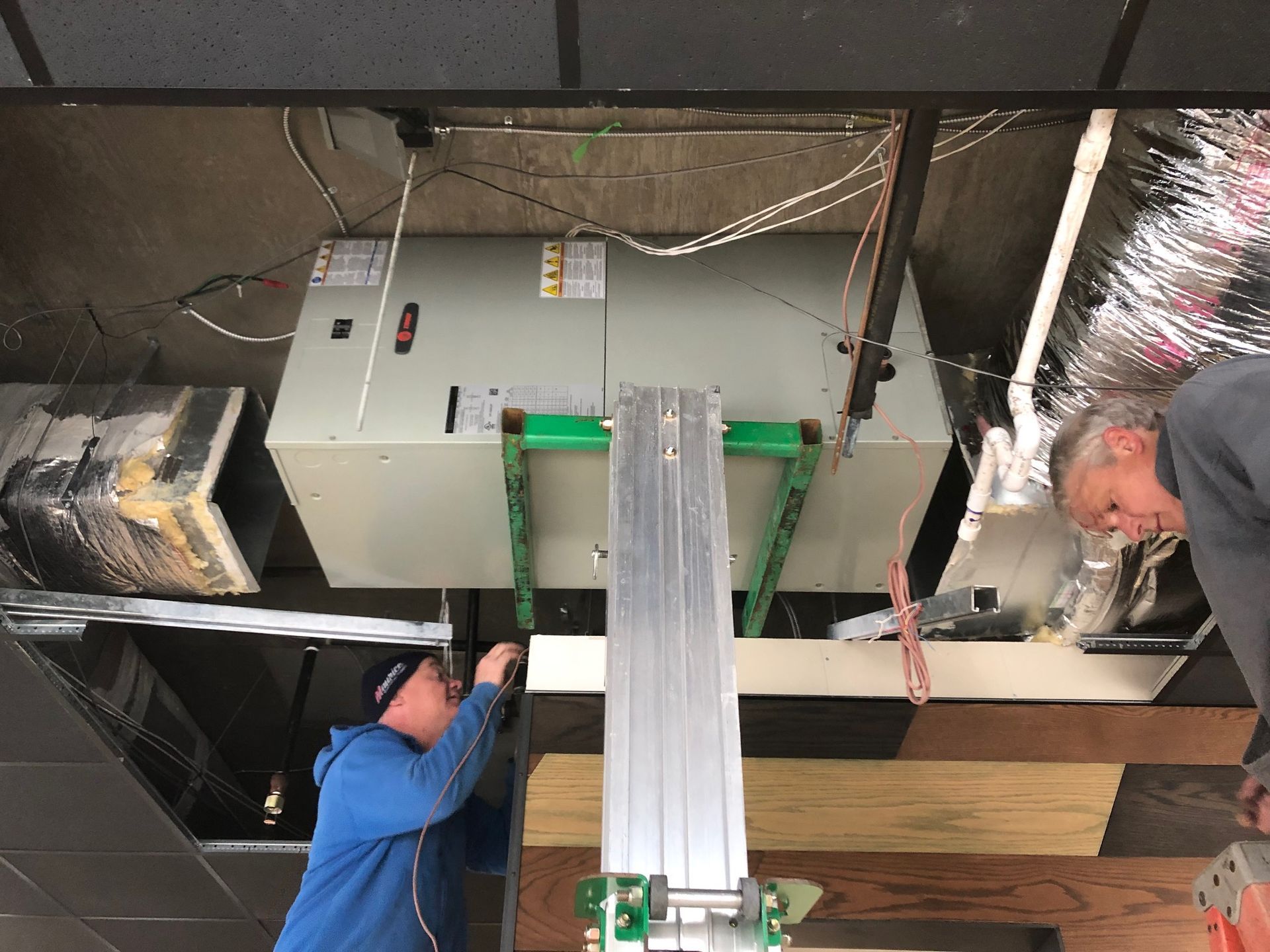 two men are working on a vent in a room