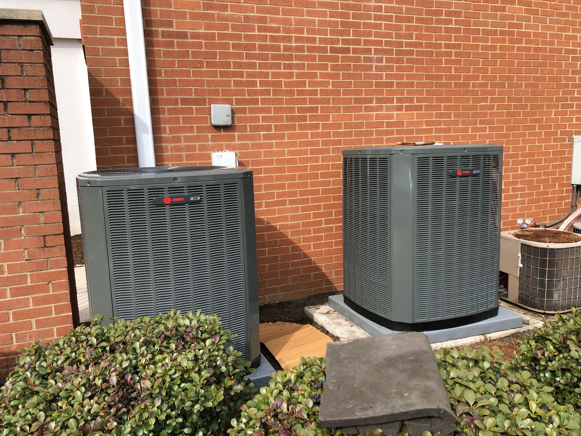 two air conditioners are sitting on the side of a brick building