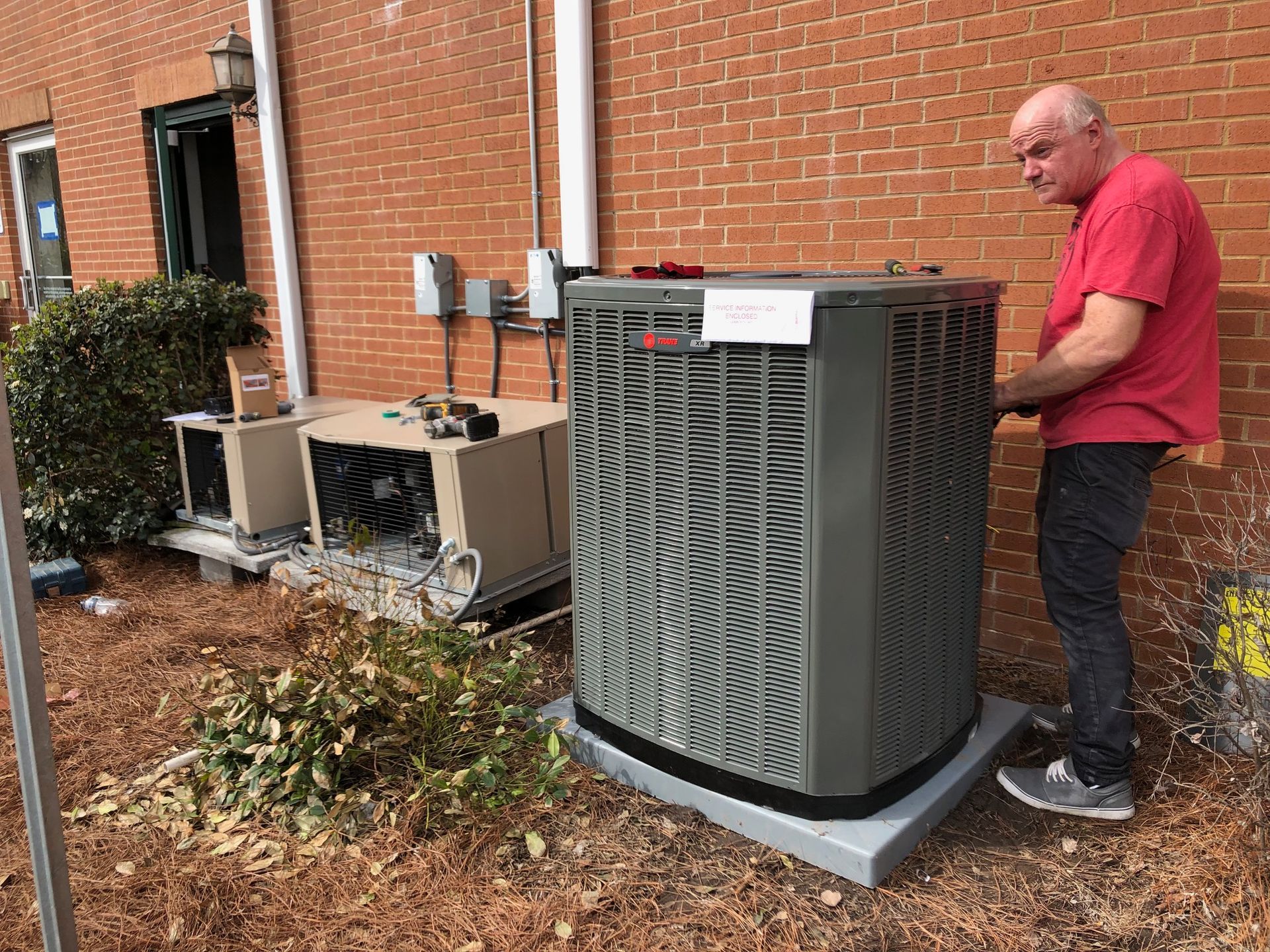 a man is working on an air conditioner outside of a brick building