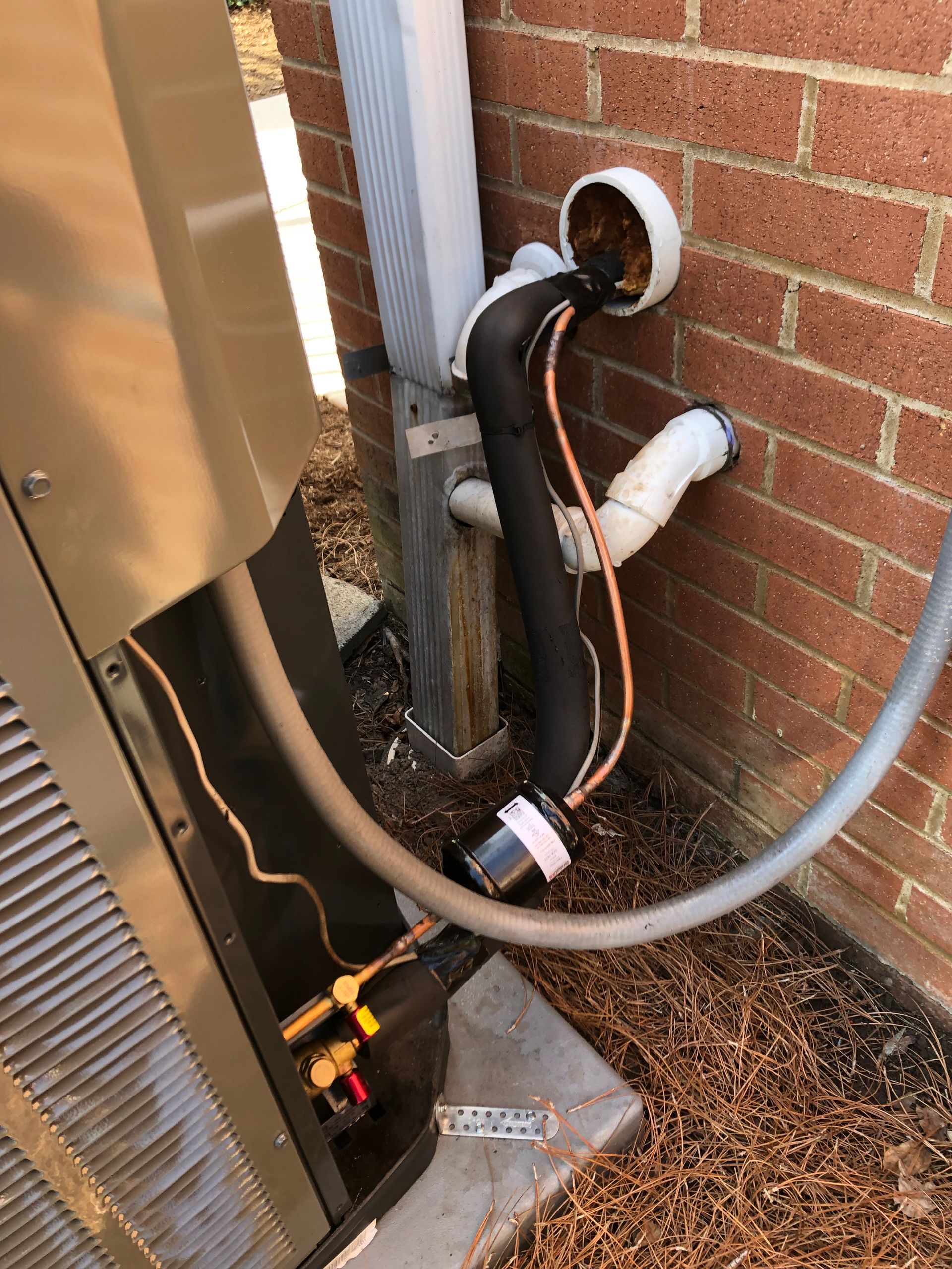 a hose is attached to a brick wall next to an air conditioner